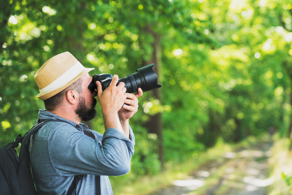 Male photographer with backpack and camera taking a photo. Travel Lifestyle hobby concept... by Andrea Obzerova on 500px.com