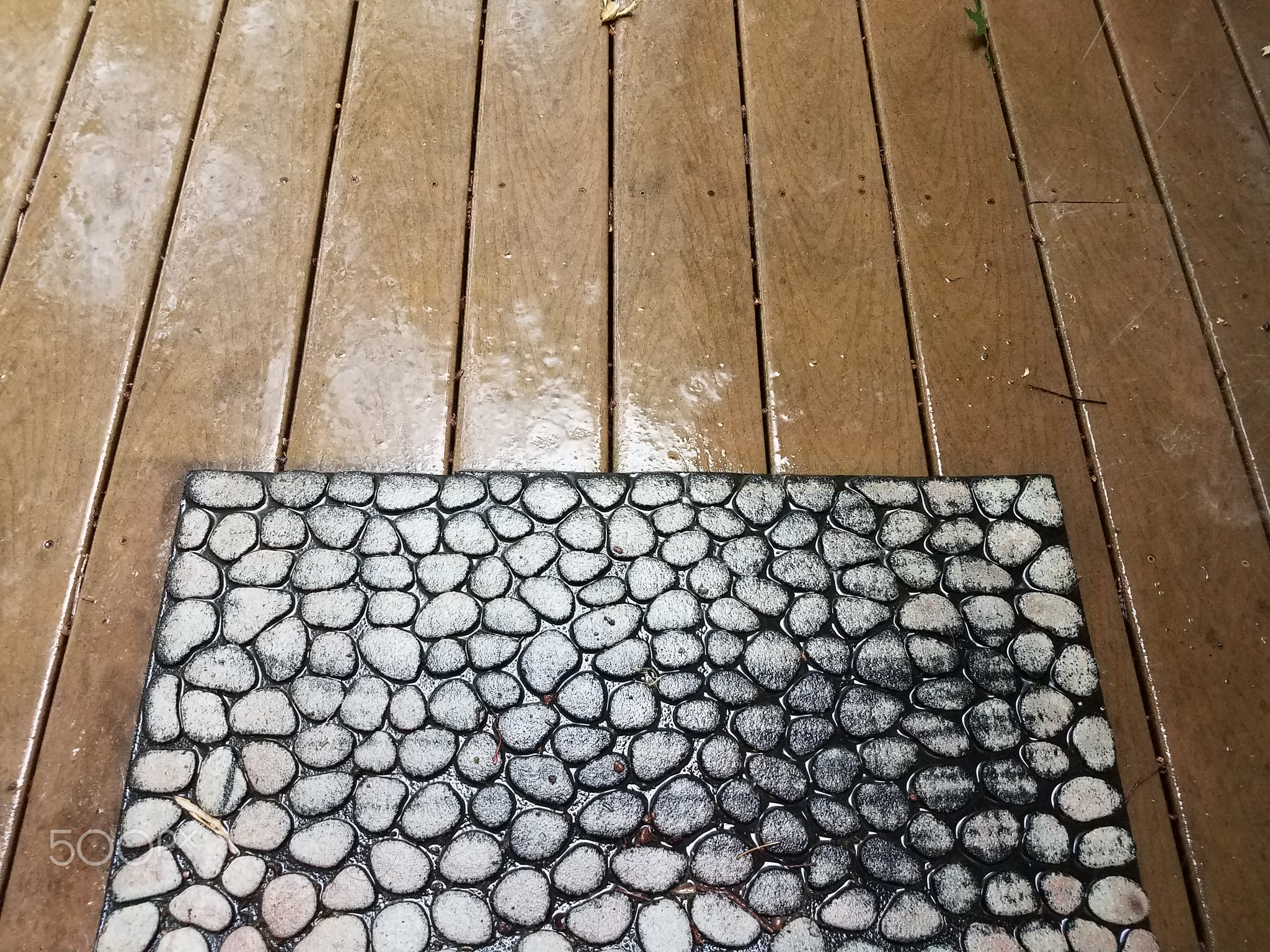 wood deck with water on it and welcome mat