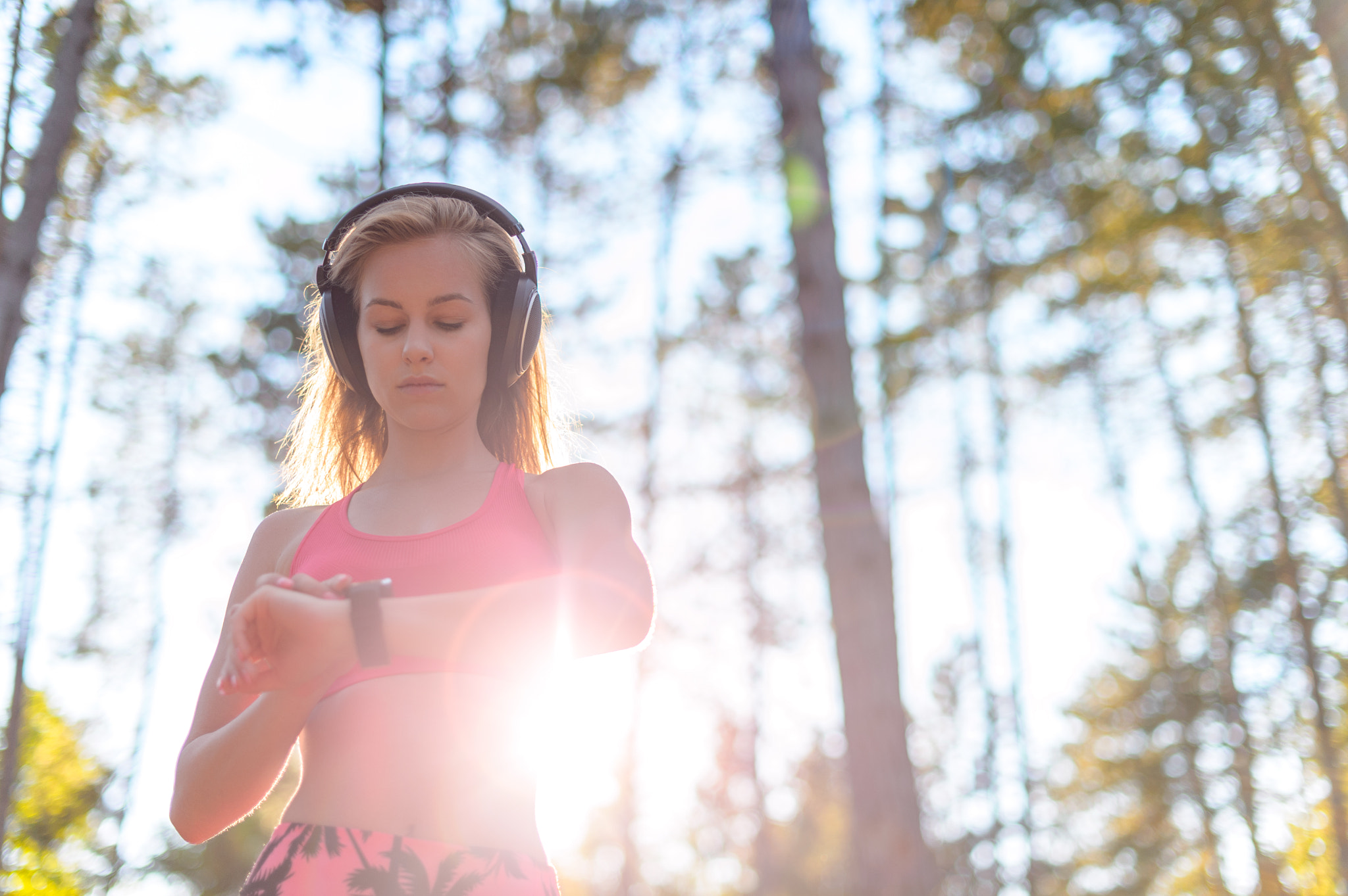 Young attractive sportswoman listening to music wearing headphones and checking her smart watch....