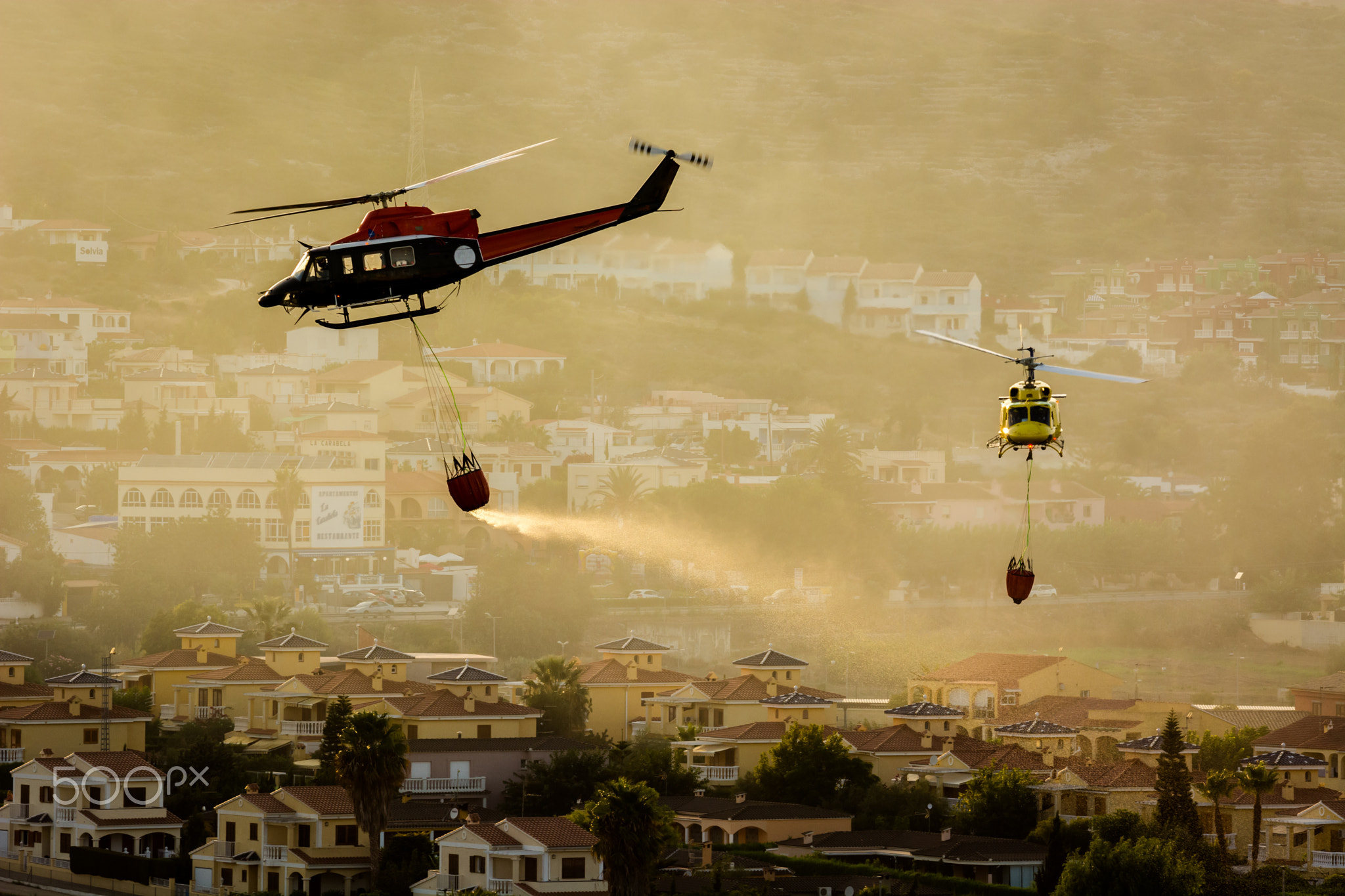 Two firefighter helicopters extinguishing a fire