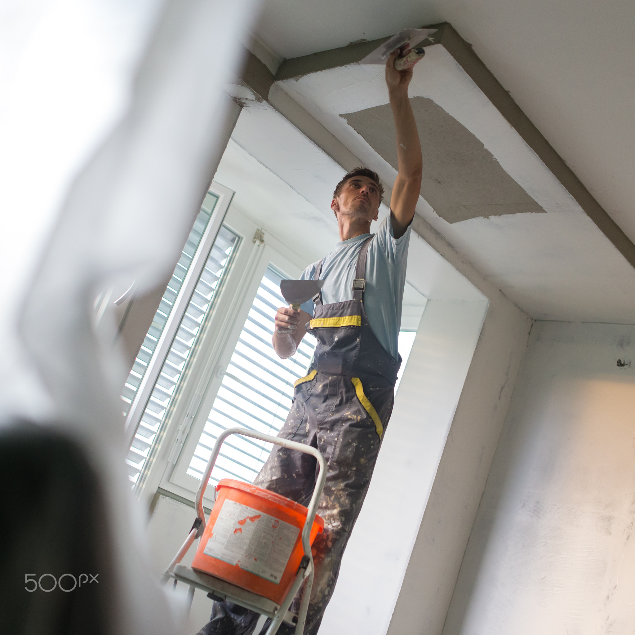 Plasterer renovating indoor walls and ceilings. Construction finishing works.