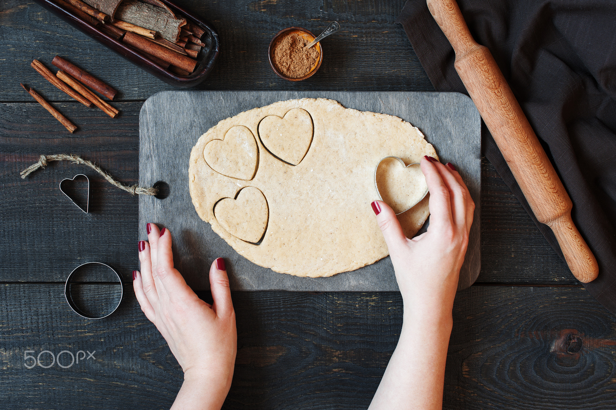 Female hands cut the cookies-hearts from the dough