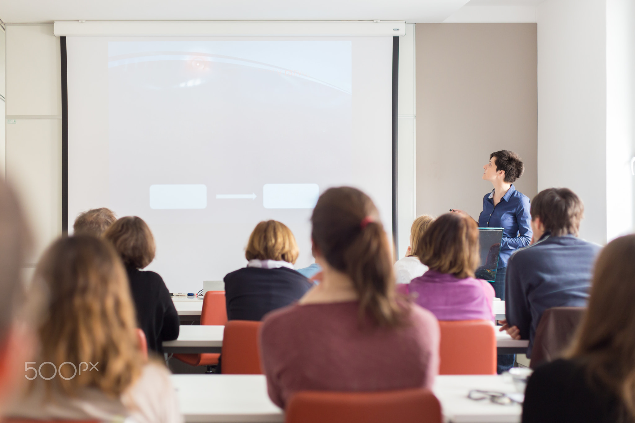Woman giving presentation in lecture hall at university.