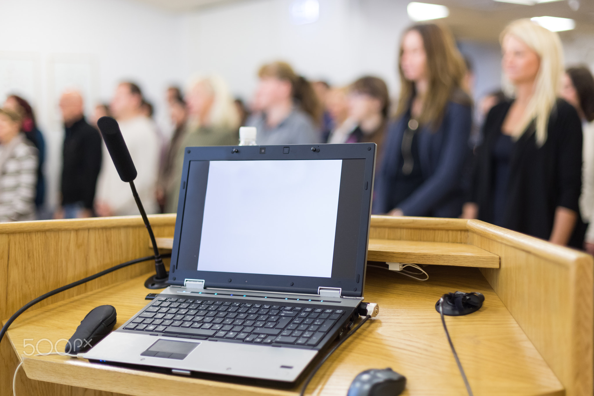 Laptop computer and microphotone at podium on business conference event.