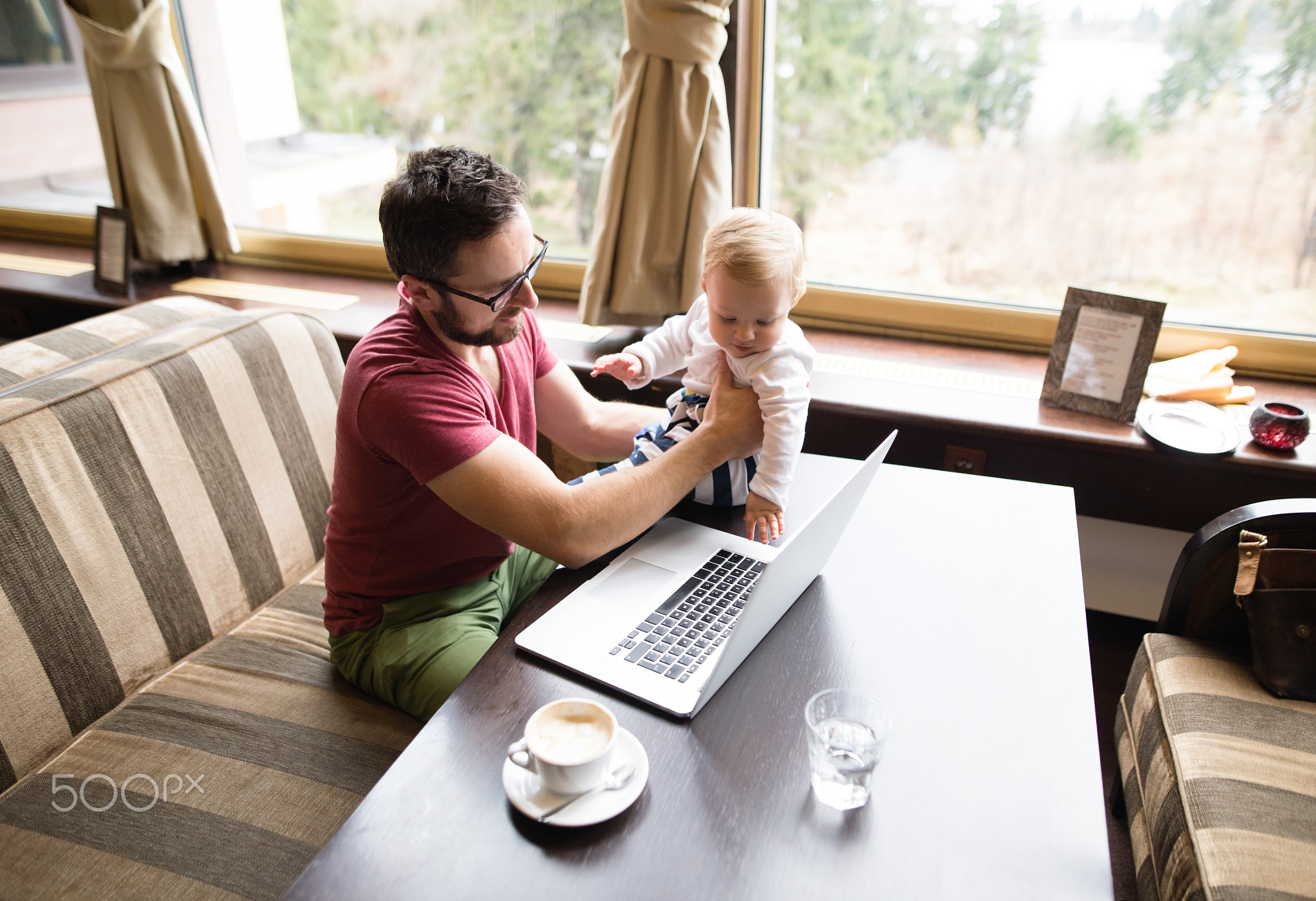 Man with notebook in cafe drinking coffee, holding his son