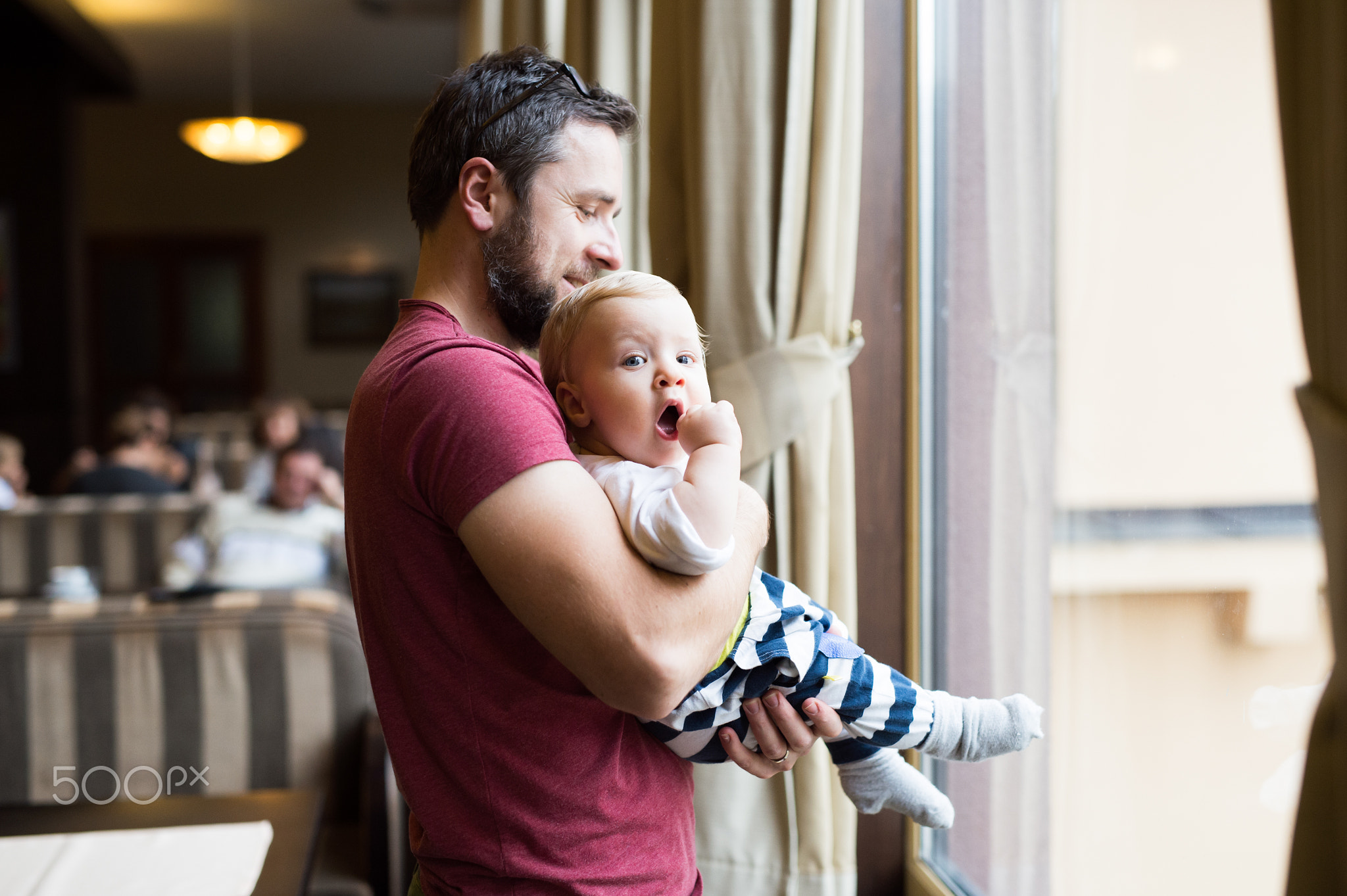 Handsome young man in cafe with his cute baby son