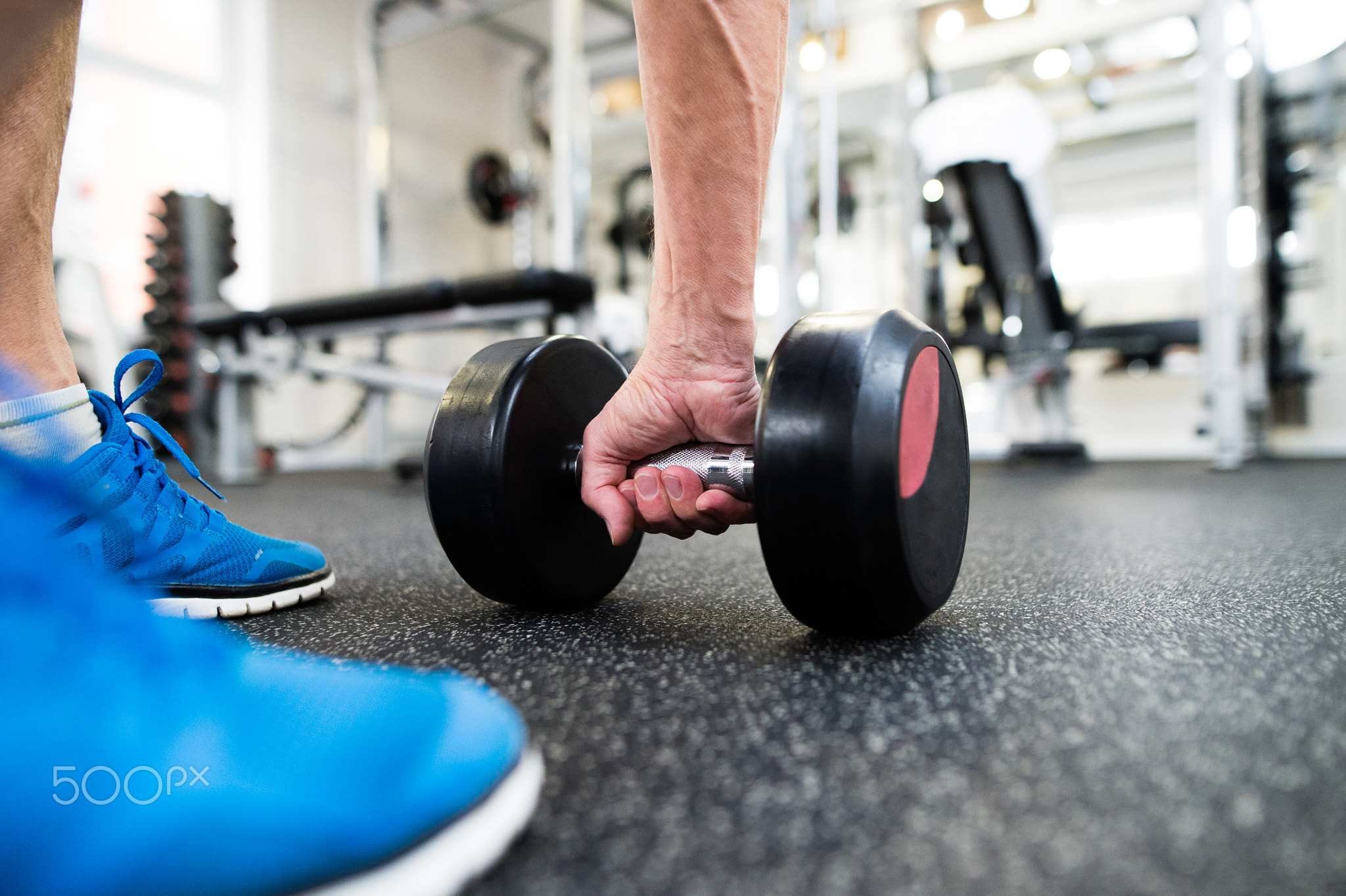 Unrecognizable senior man in gym working out with weights