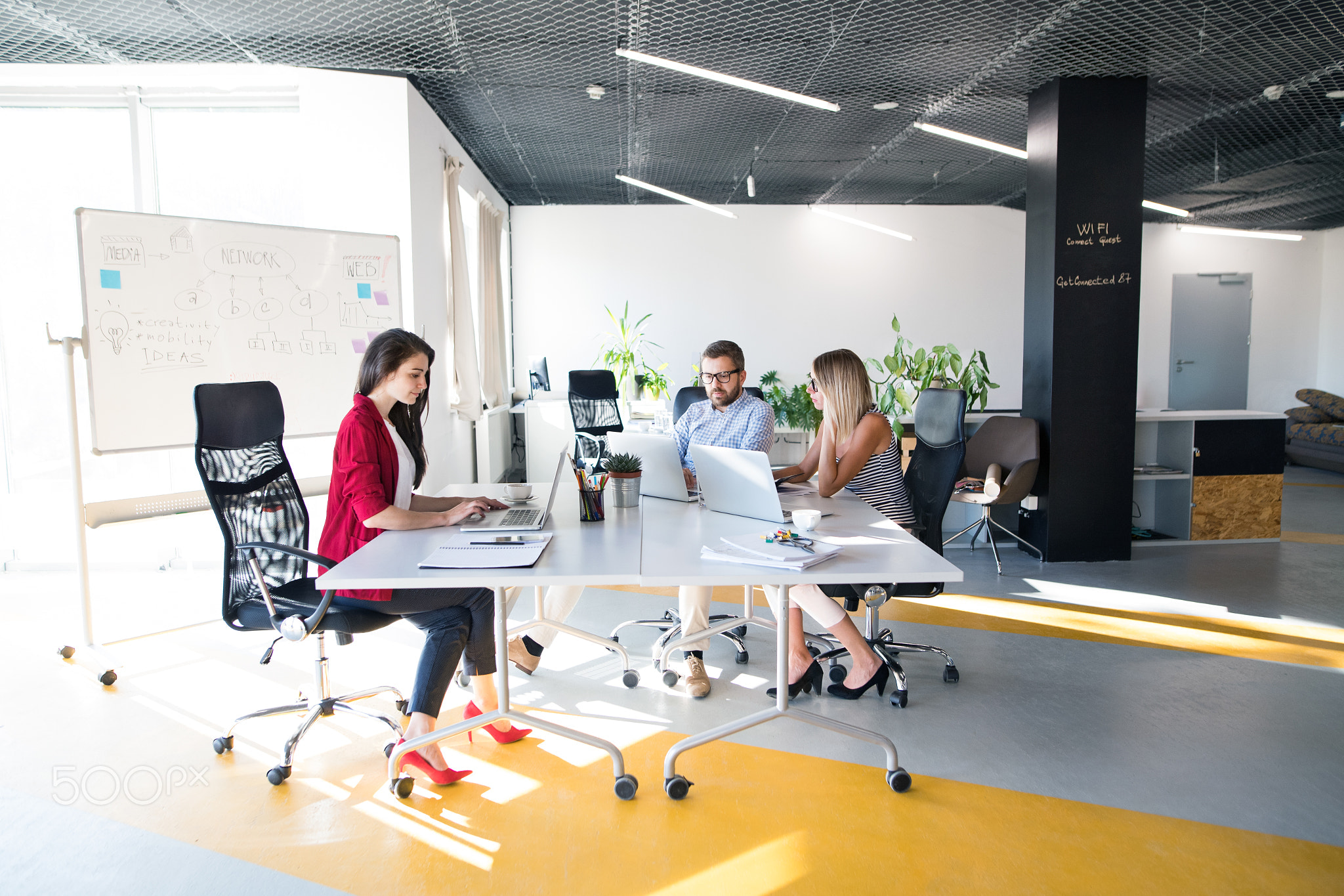 Three business people in the office talking together.