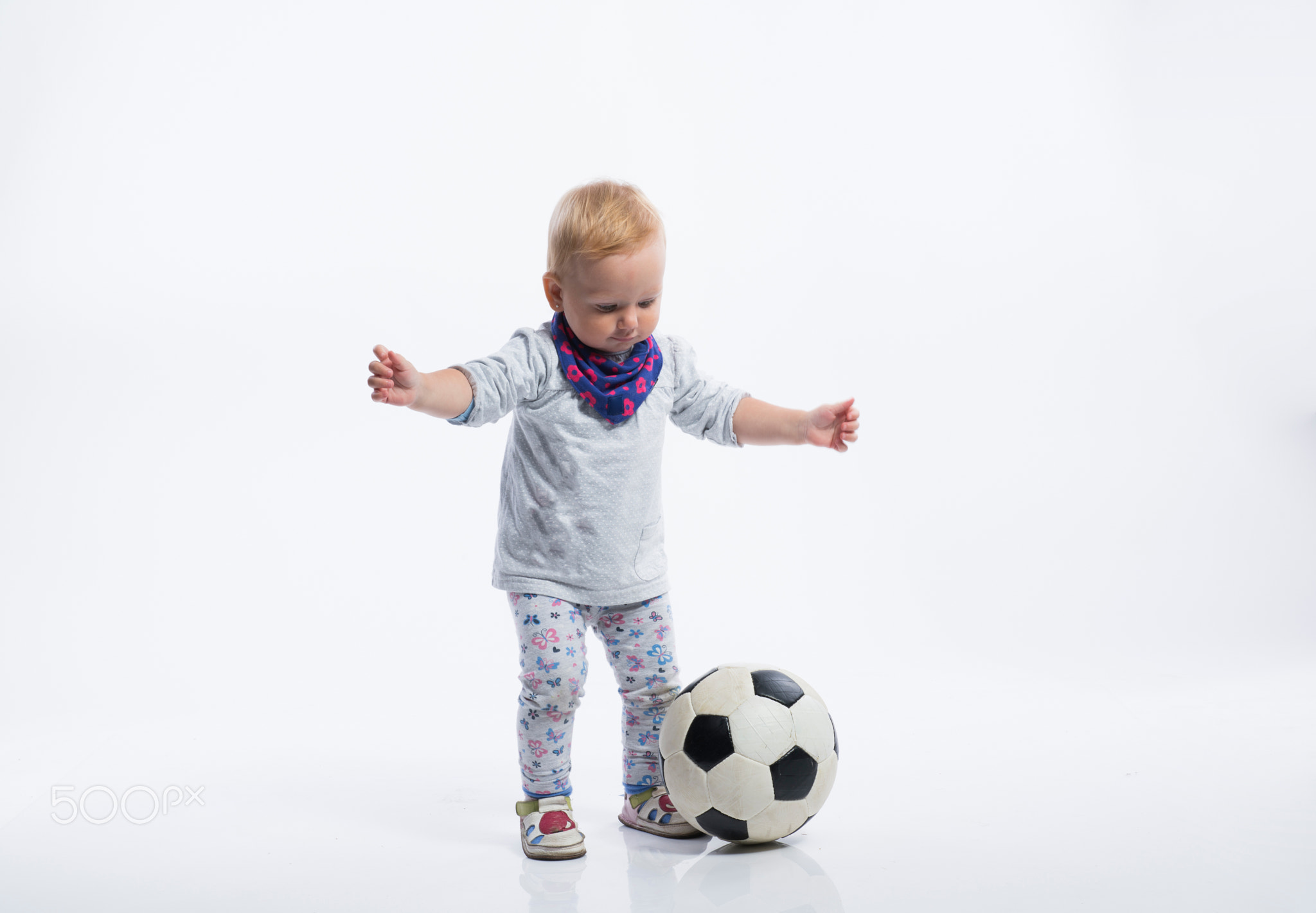 Cute little girl playing with soccer ball. Studio shot.