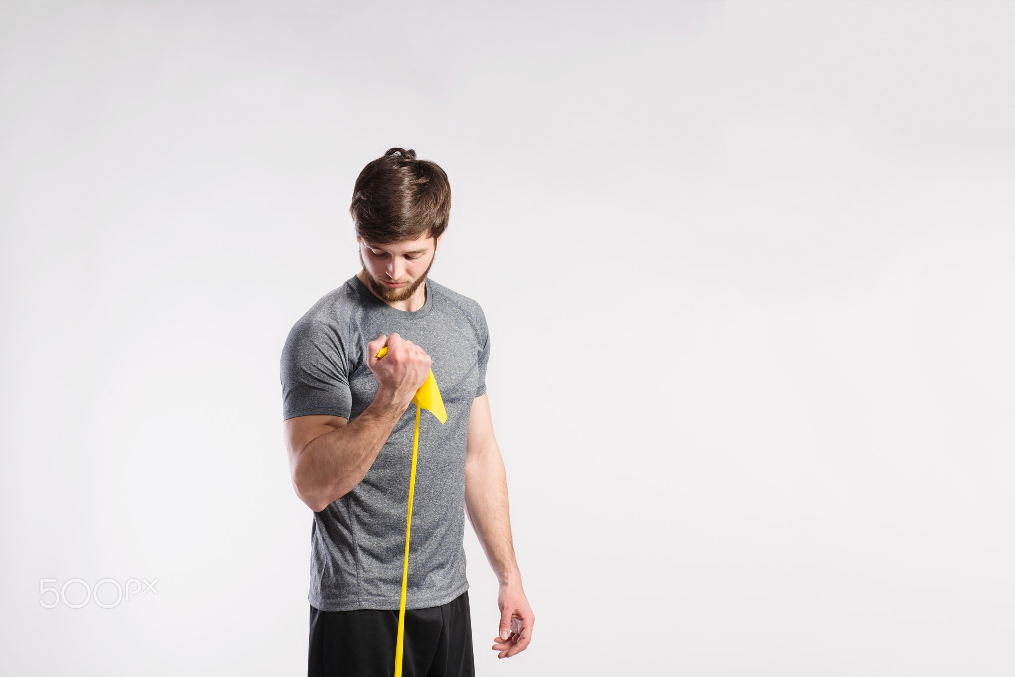 Handsome fitness man working out with rubber band, studio shot.