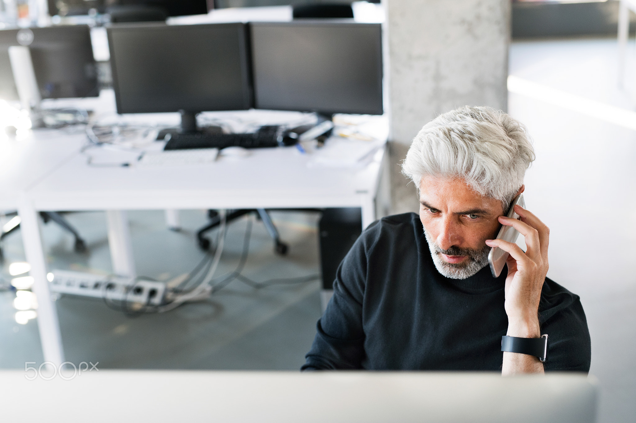 Mature businessman in the office making a phone call.