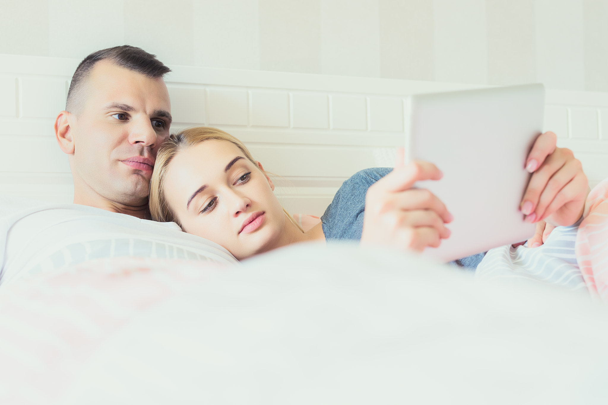 Young attractive couple in bed, using digital tablet.