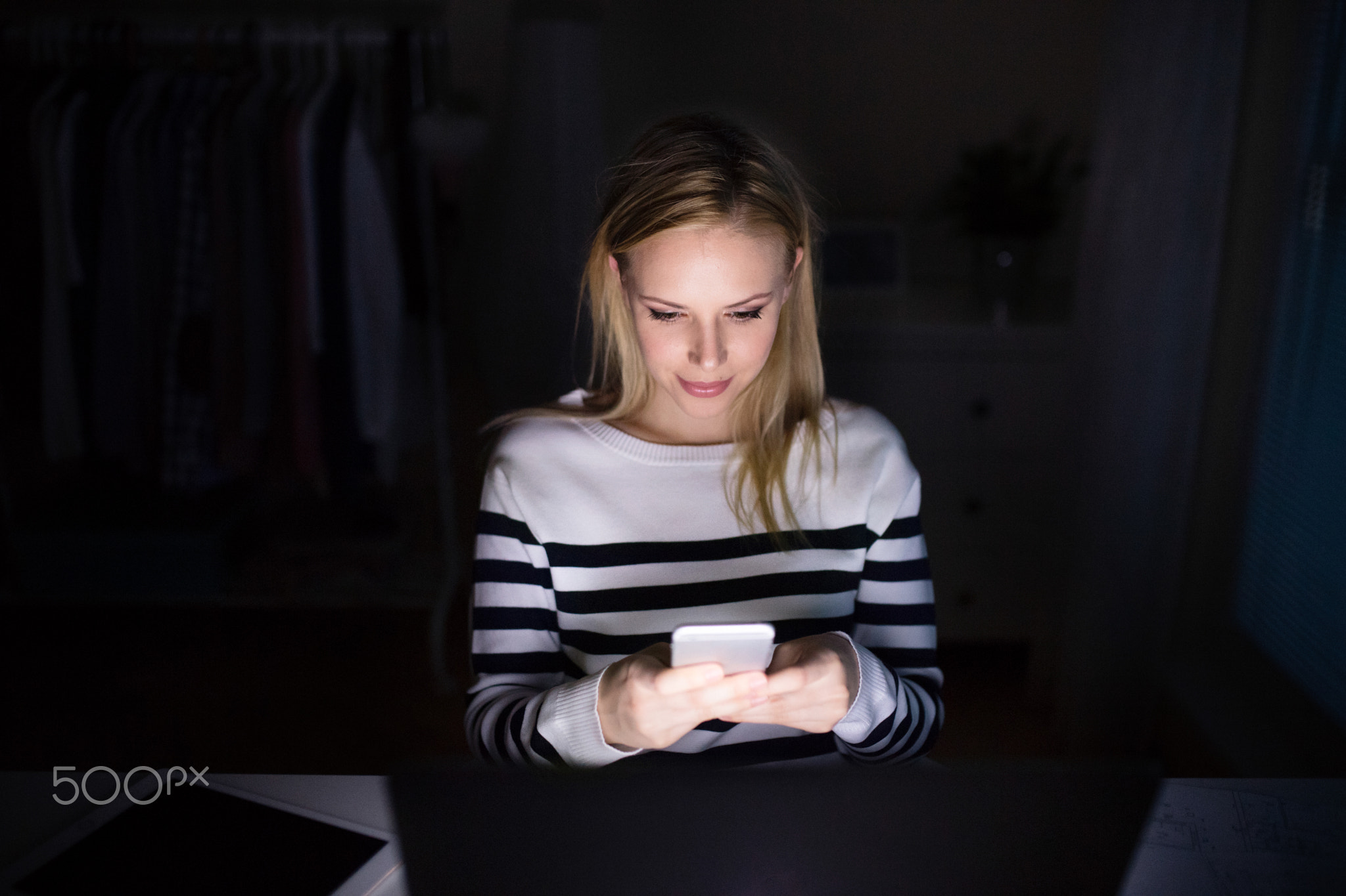 Woman with laptop and smartphone, texting.
