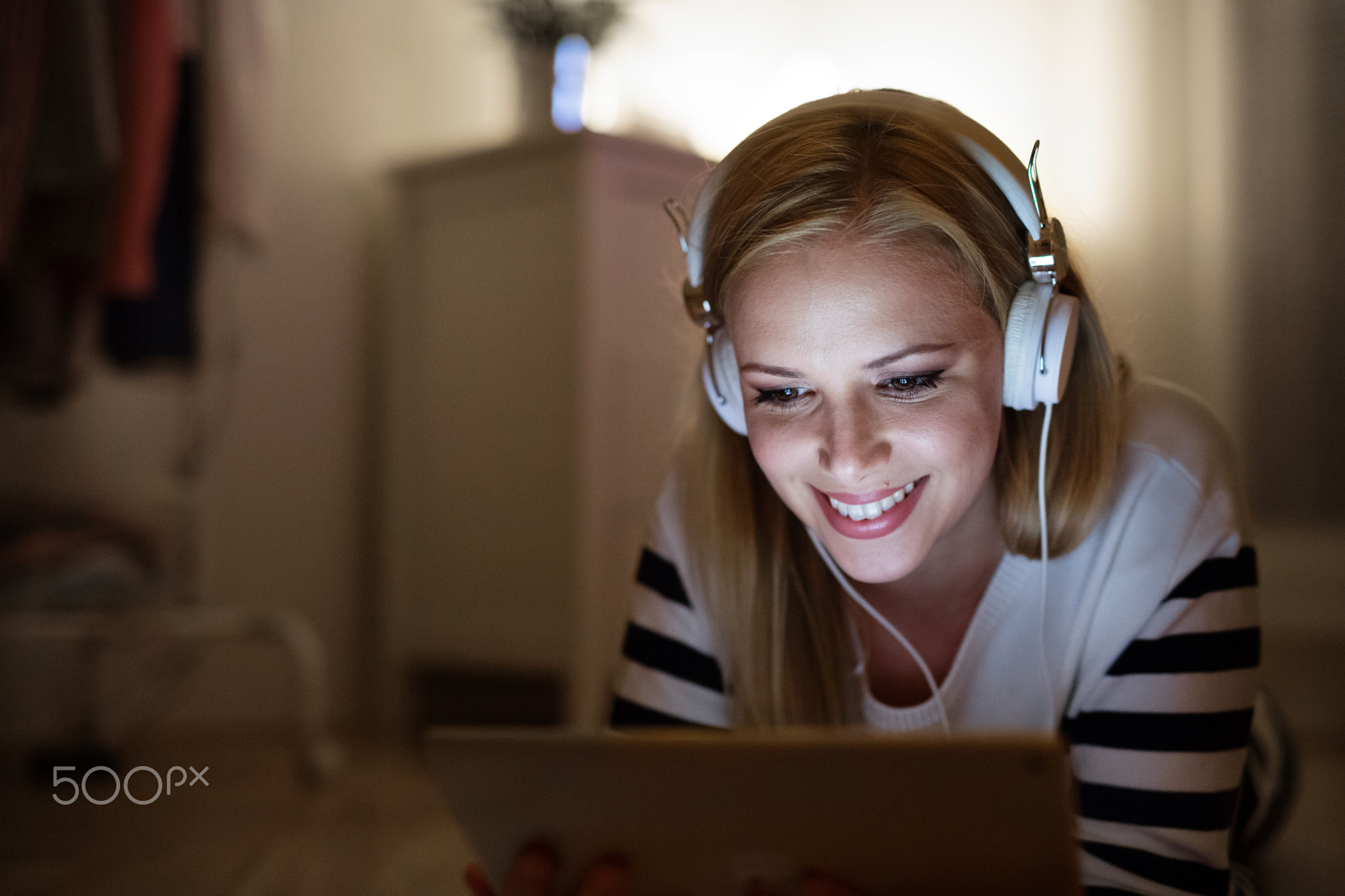 Woman lying on the floor, working on tablet at night.