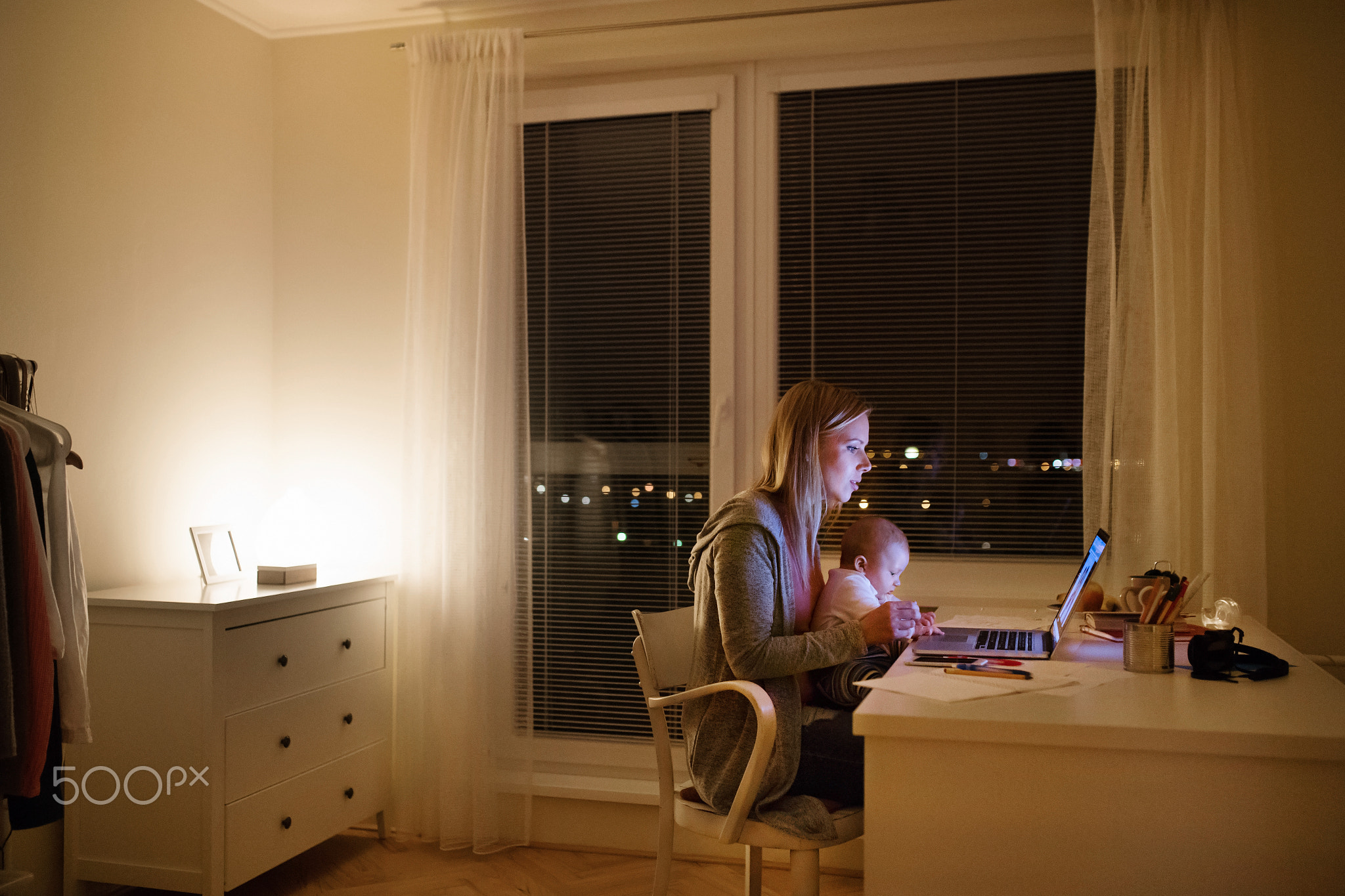 Mother with son in the arms, working on laptop