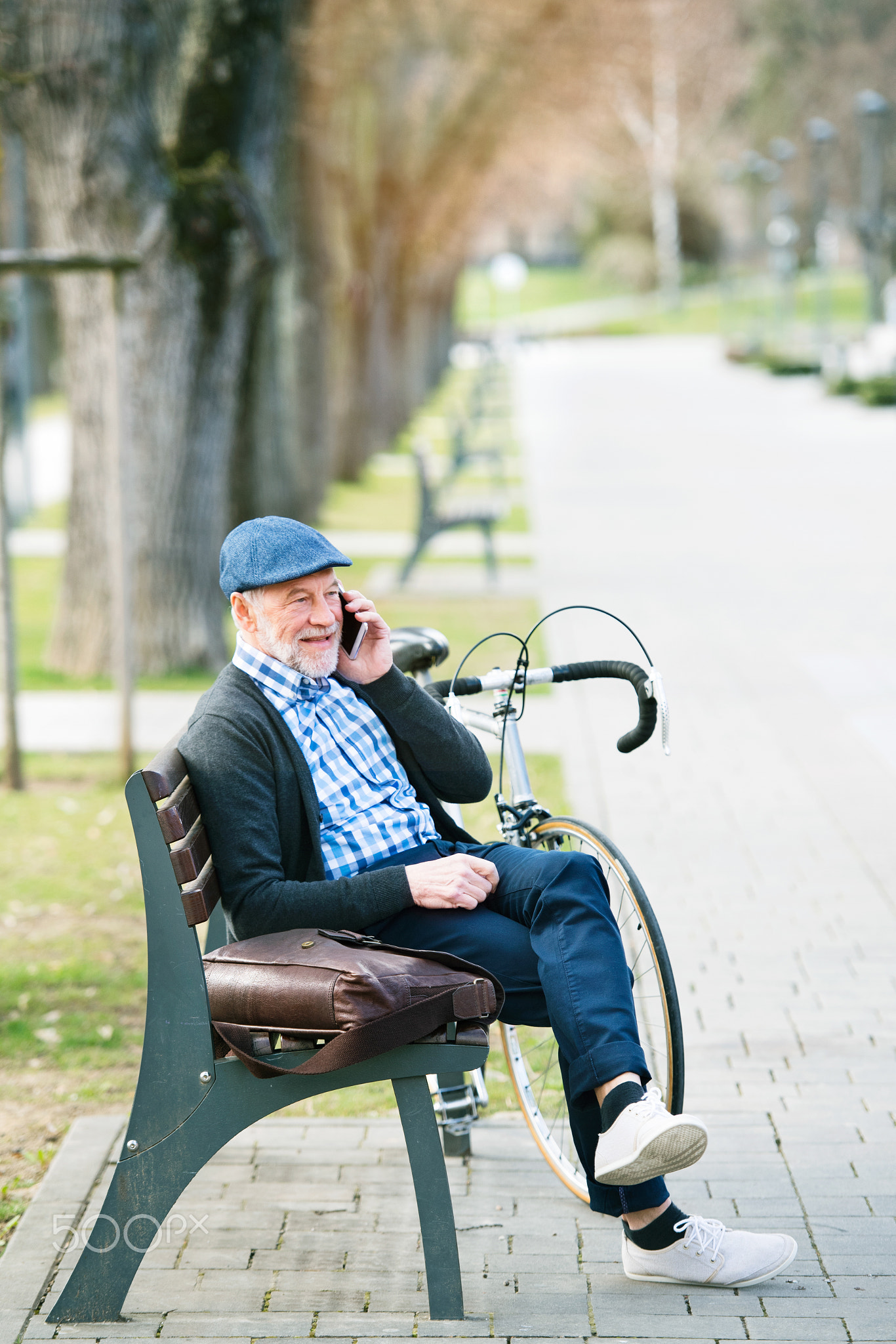 Senior man with bicycle and smart phone, making phone call