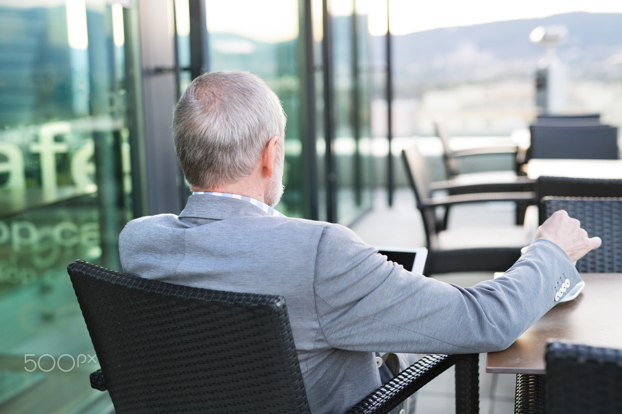 Senior businessman with a tablet in rooftop cafe