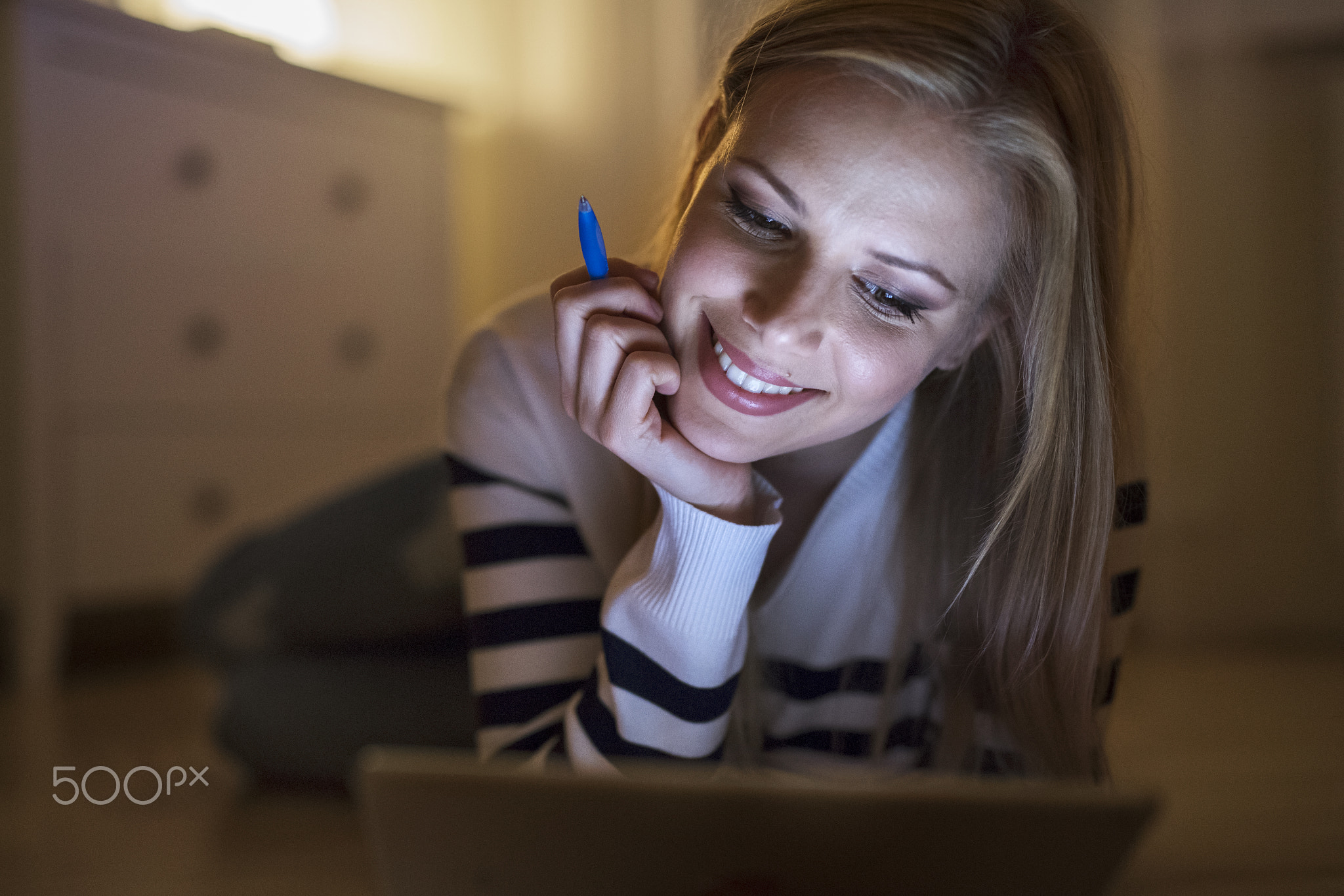 Woman lying on the floor, working on tablet at night.