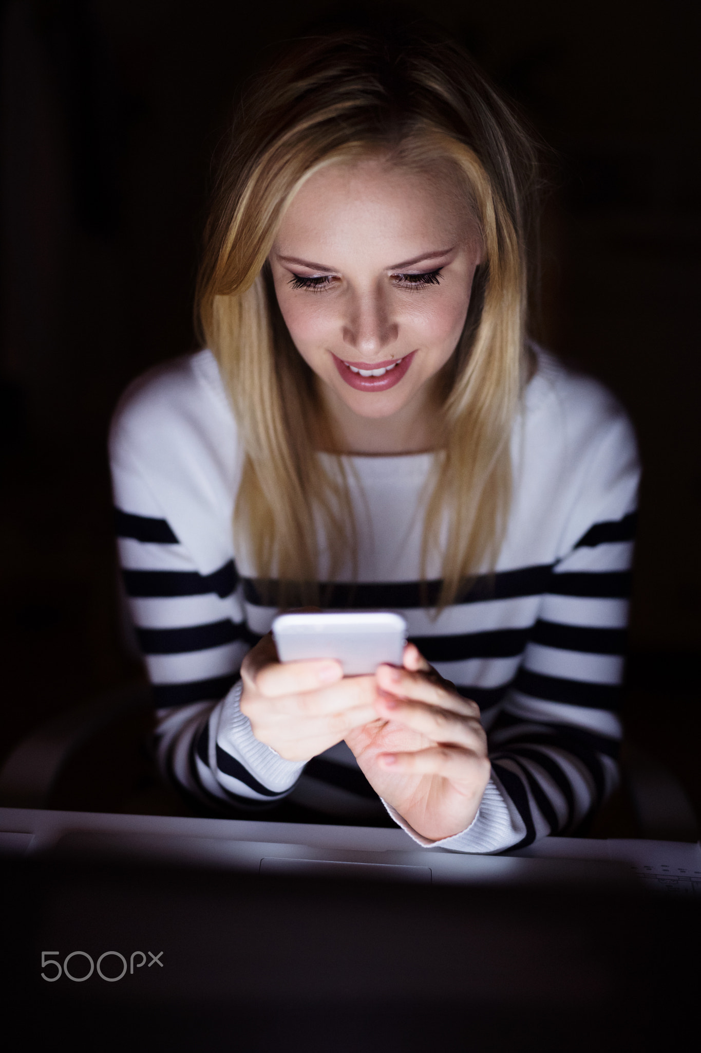 Woman with laptop and smartphone, texting.