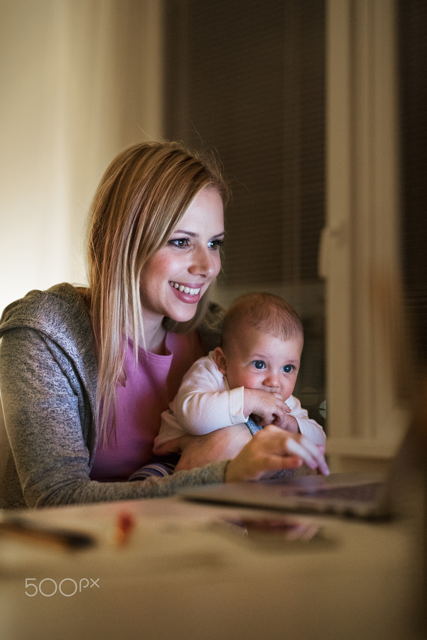 Mother with son in the arms, working on laptop