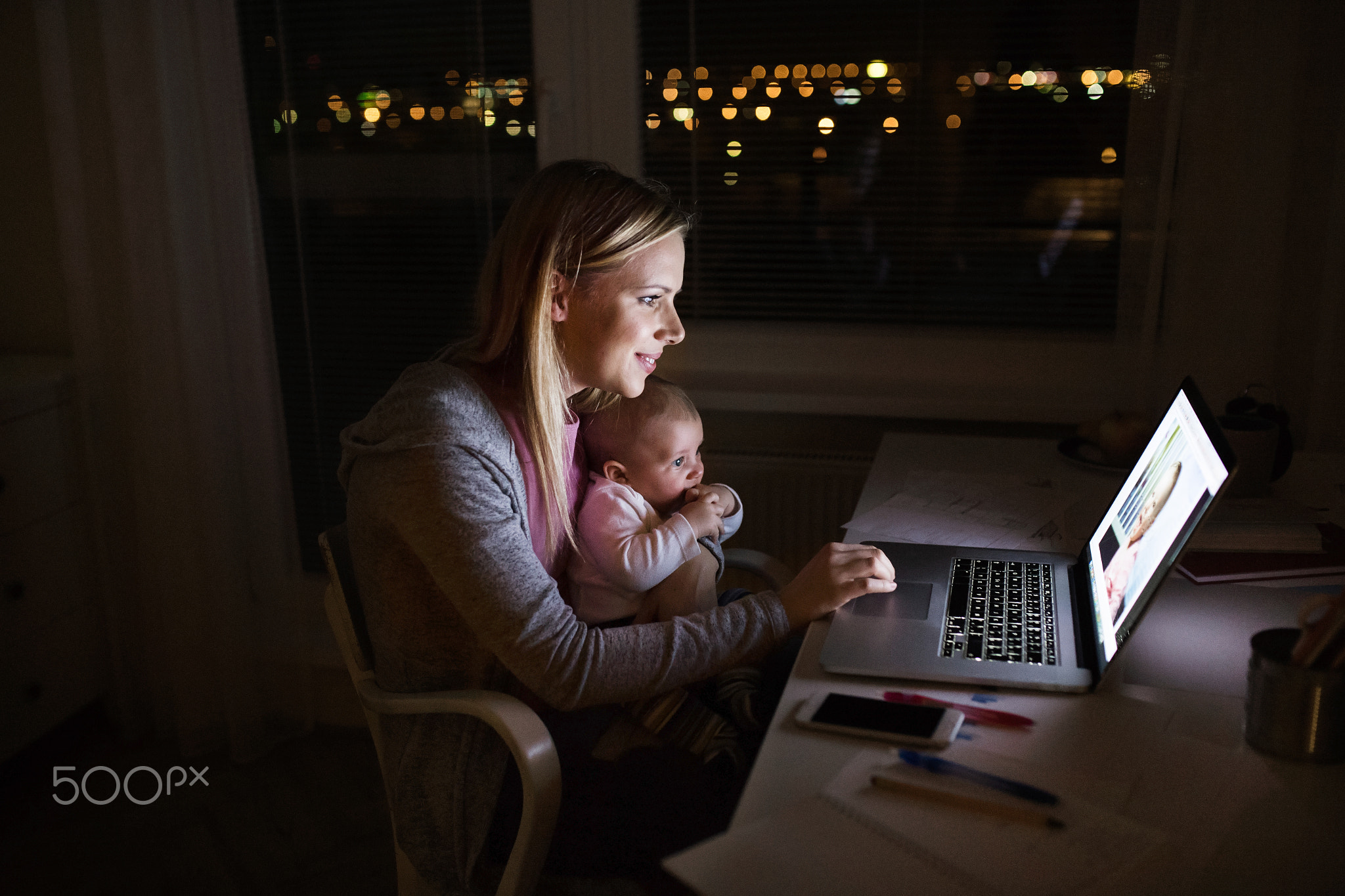 Mother with son in the arms, working on laptop