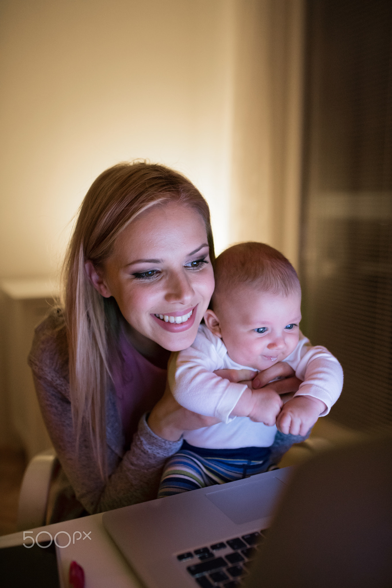 Mother with son in the arms, working on laptop