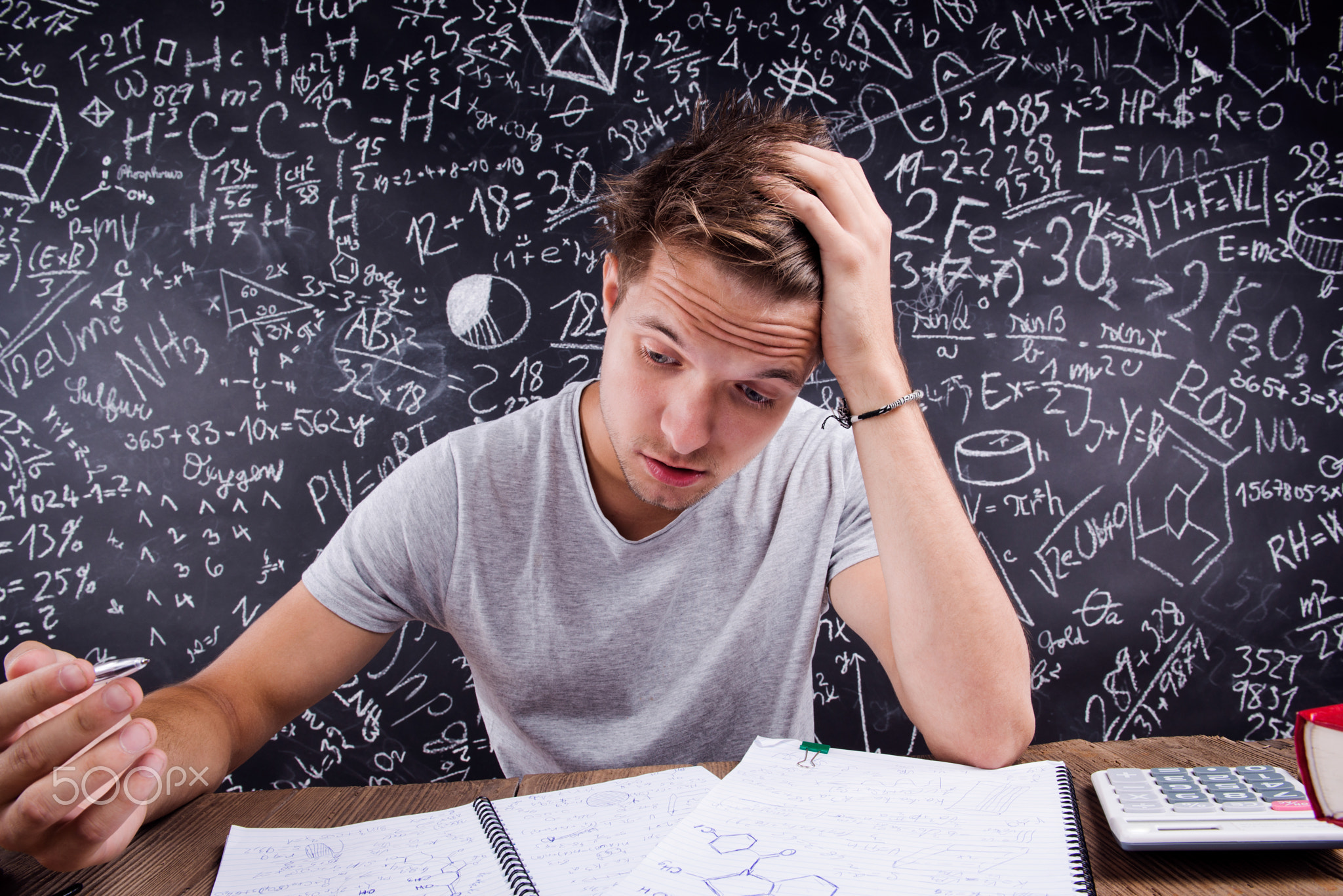 Hipster student doing his homework against a big blackboard
