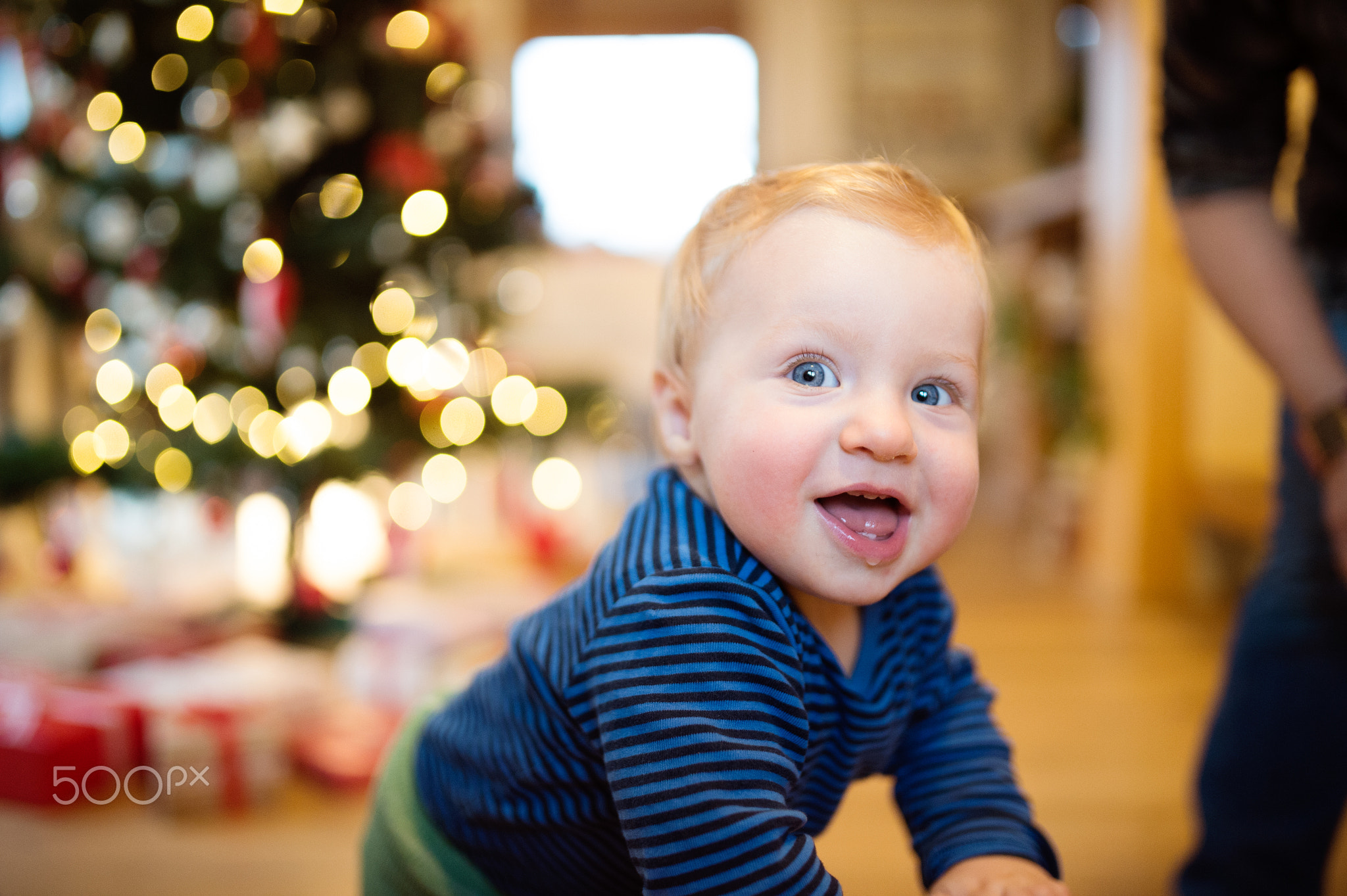 Little boy at home against Christmas tree and presents