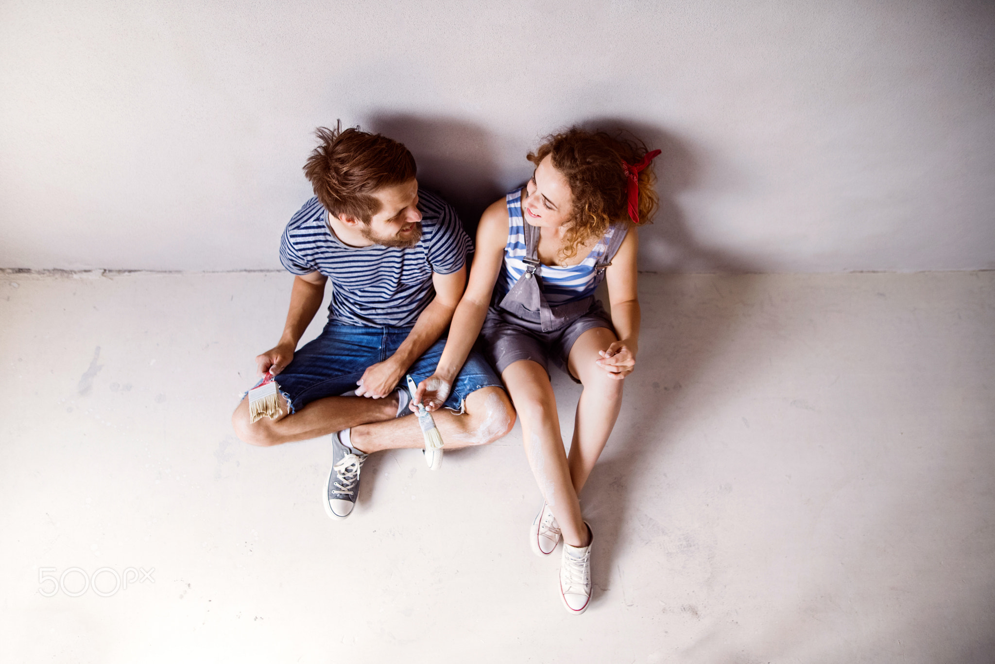 Young couple in love painting walls in their new home.