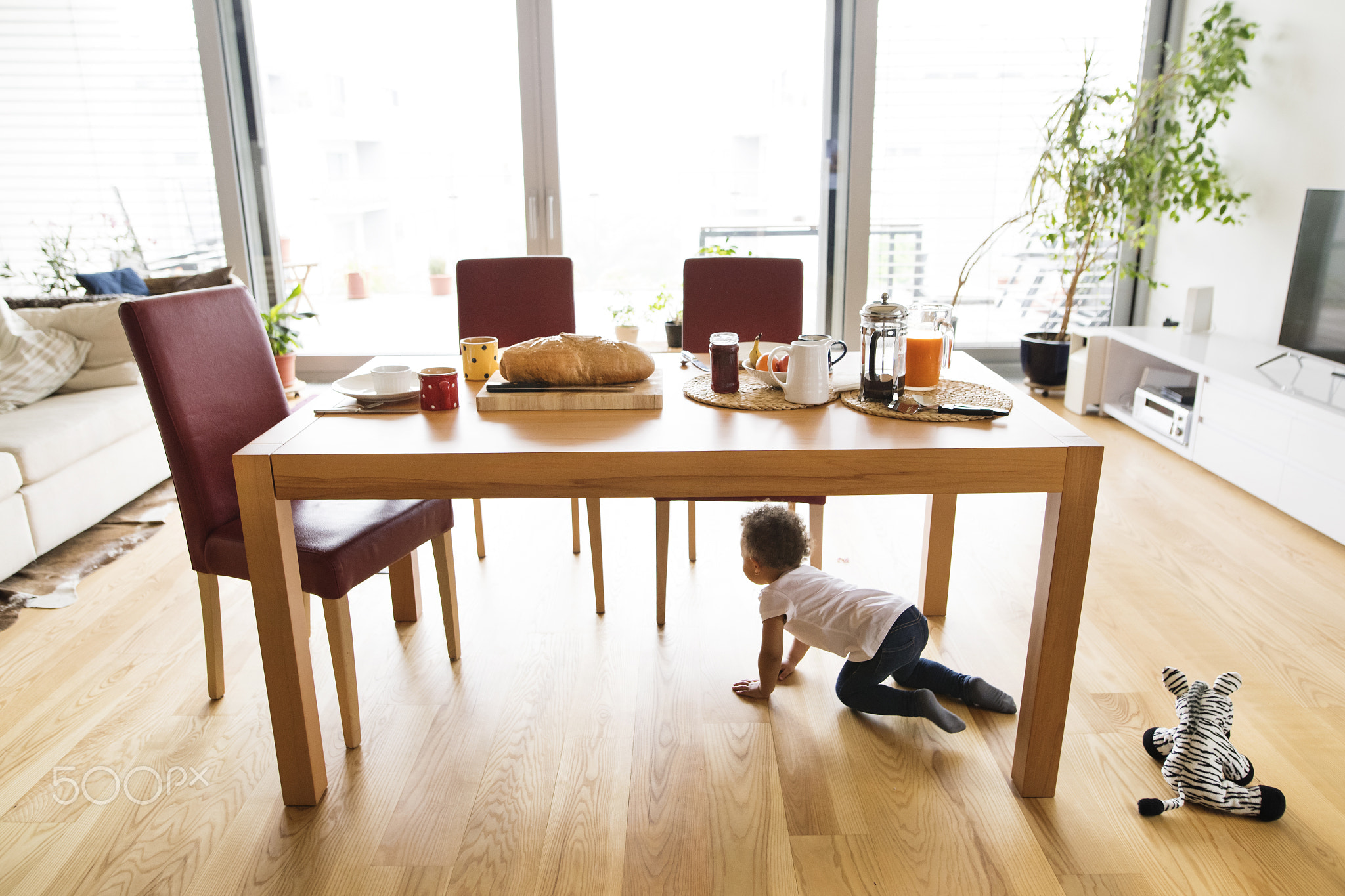 Little mixed-race girl at home under the kitchen table.