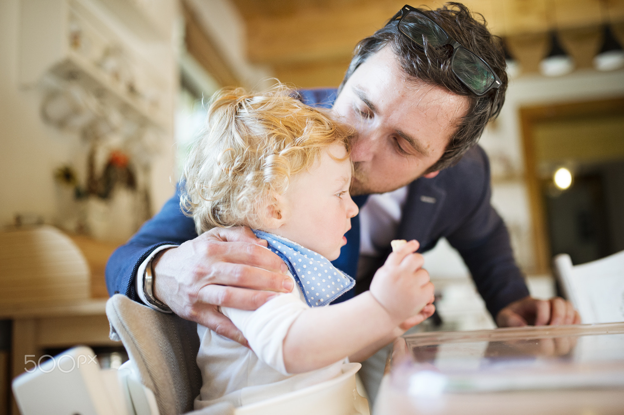 Businessman coming home, kissing little son on forehead.