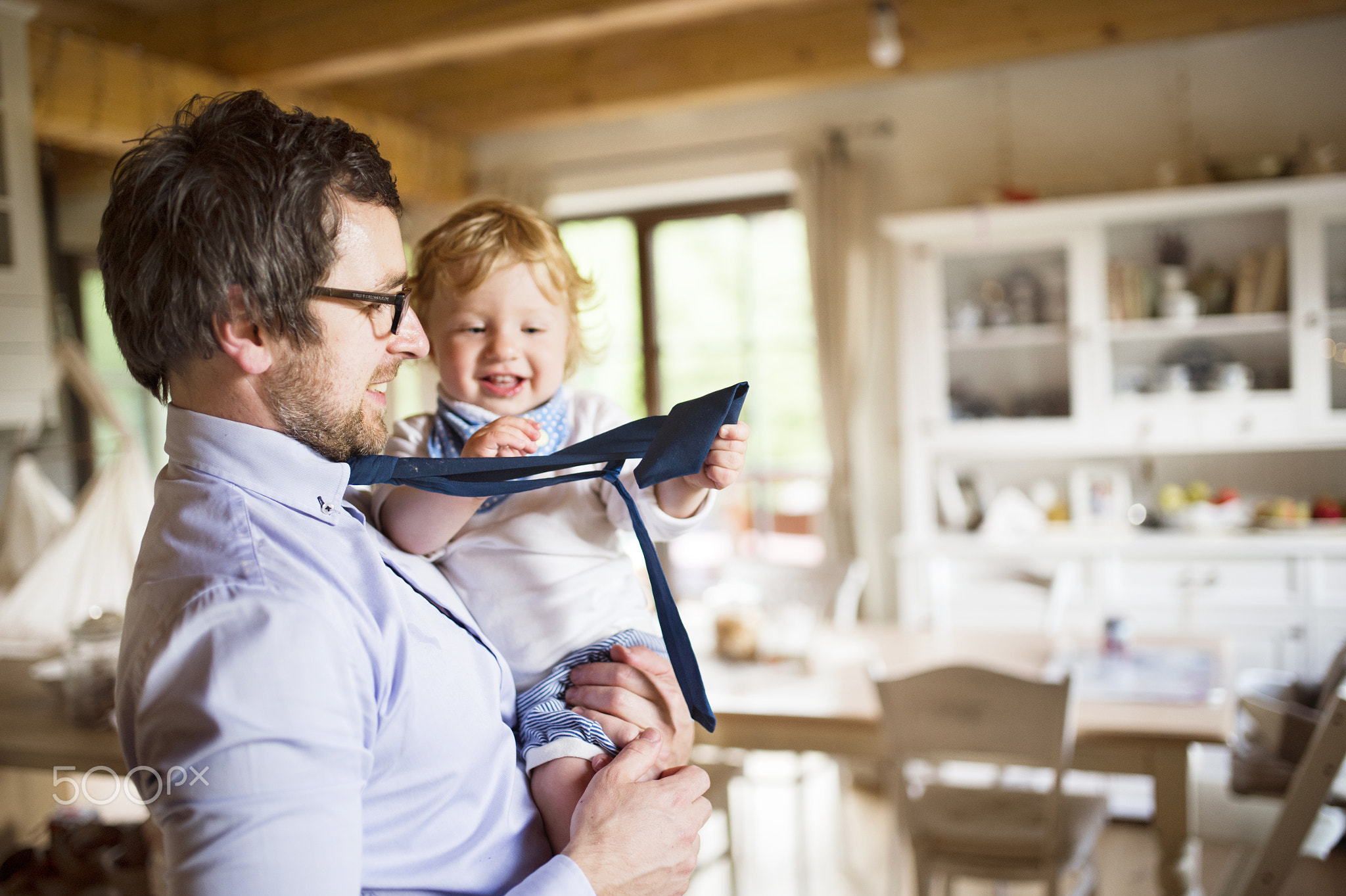 Businessman coming home, holding his son high in the arms.