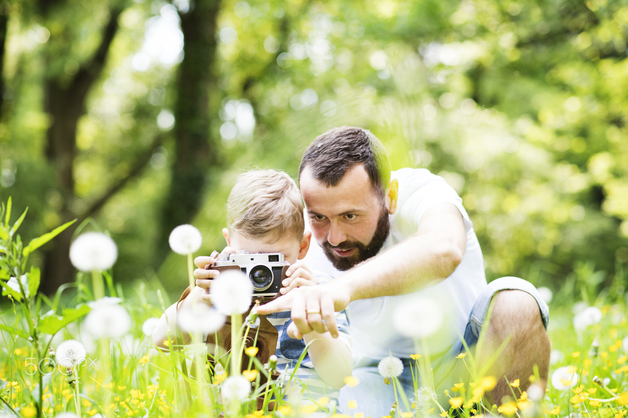 Young father with little boy with camera in summer park.