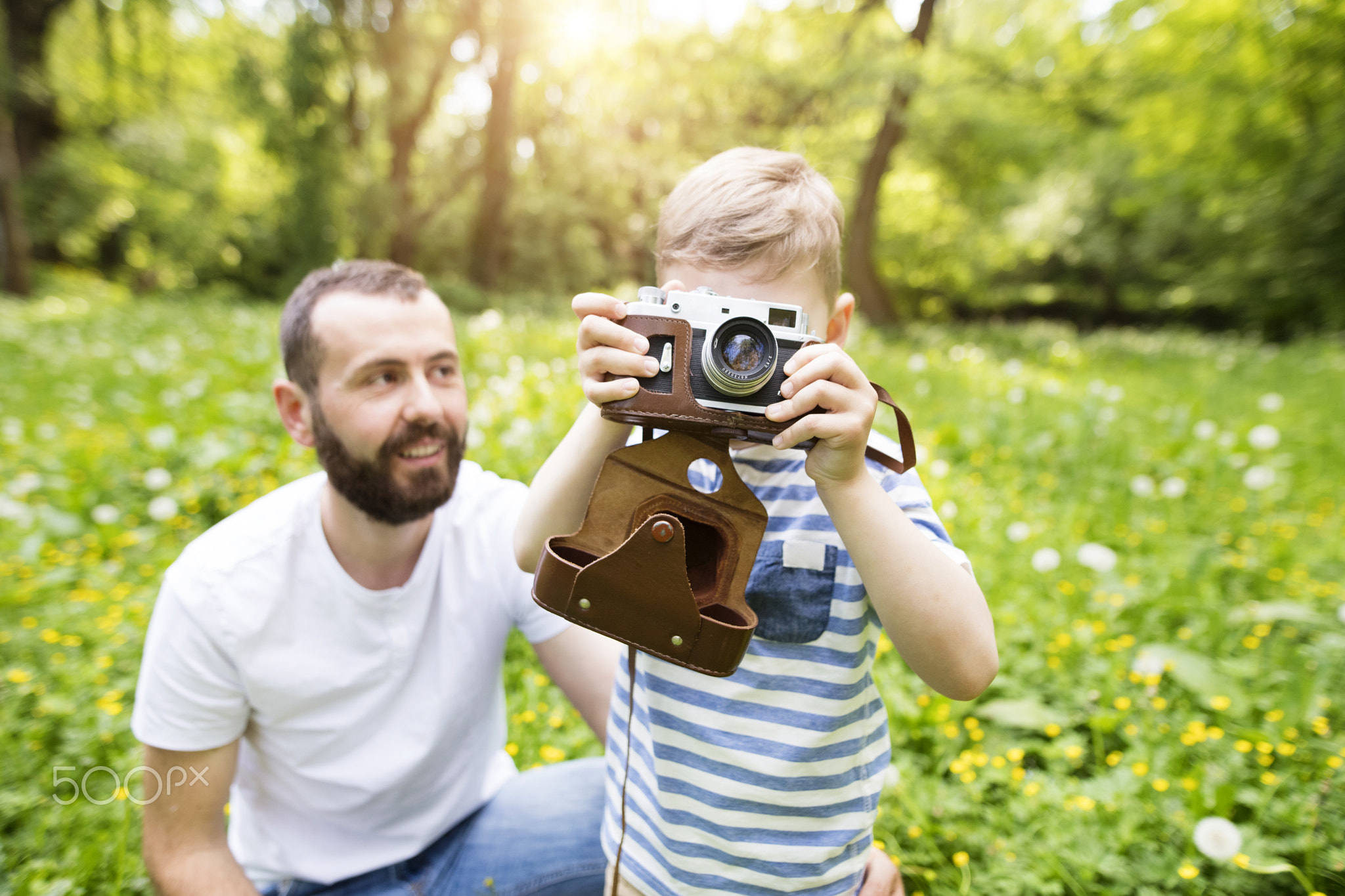 Young father with little boy with camera in summer park.