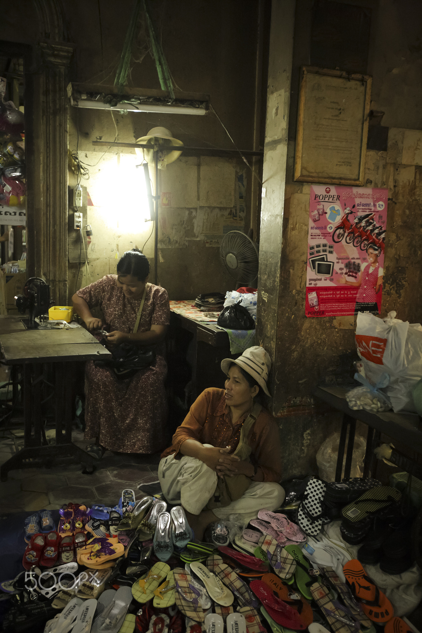Siem Reap, Cambodia 17 NOV 2007:  Street hawkers selling shoes with tailor at the back