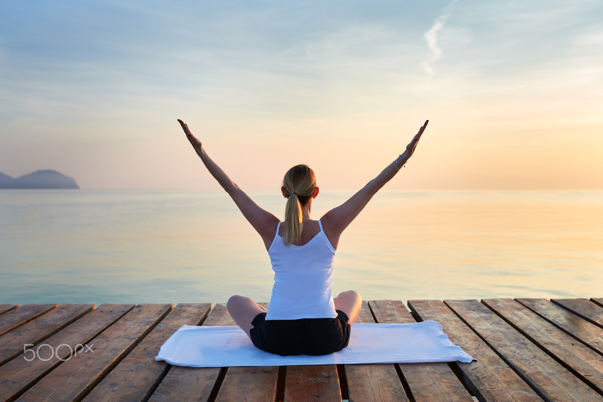 Young woman practising yoga by sea