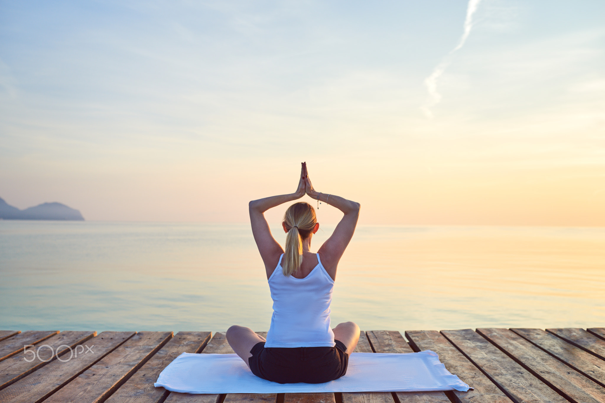 Young woman practising yoga by sea