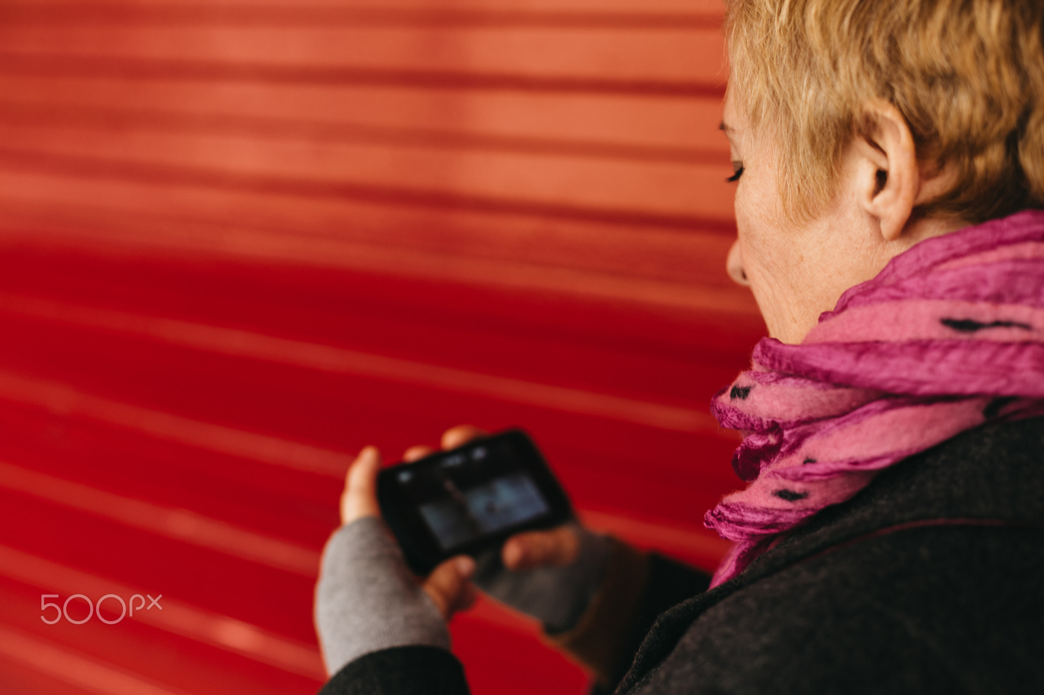 Woman texting at red wall