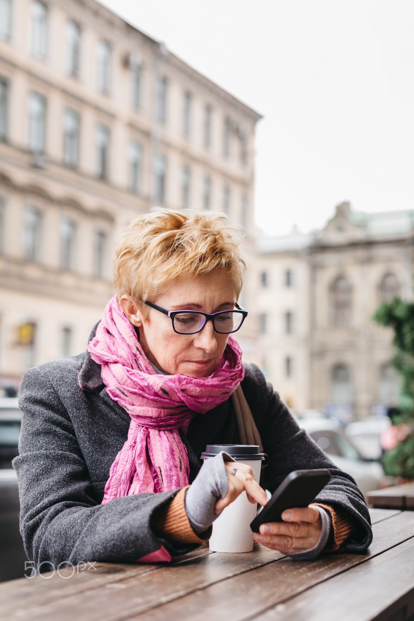 Woman browsing smartphone in outside cafe