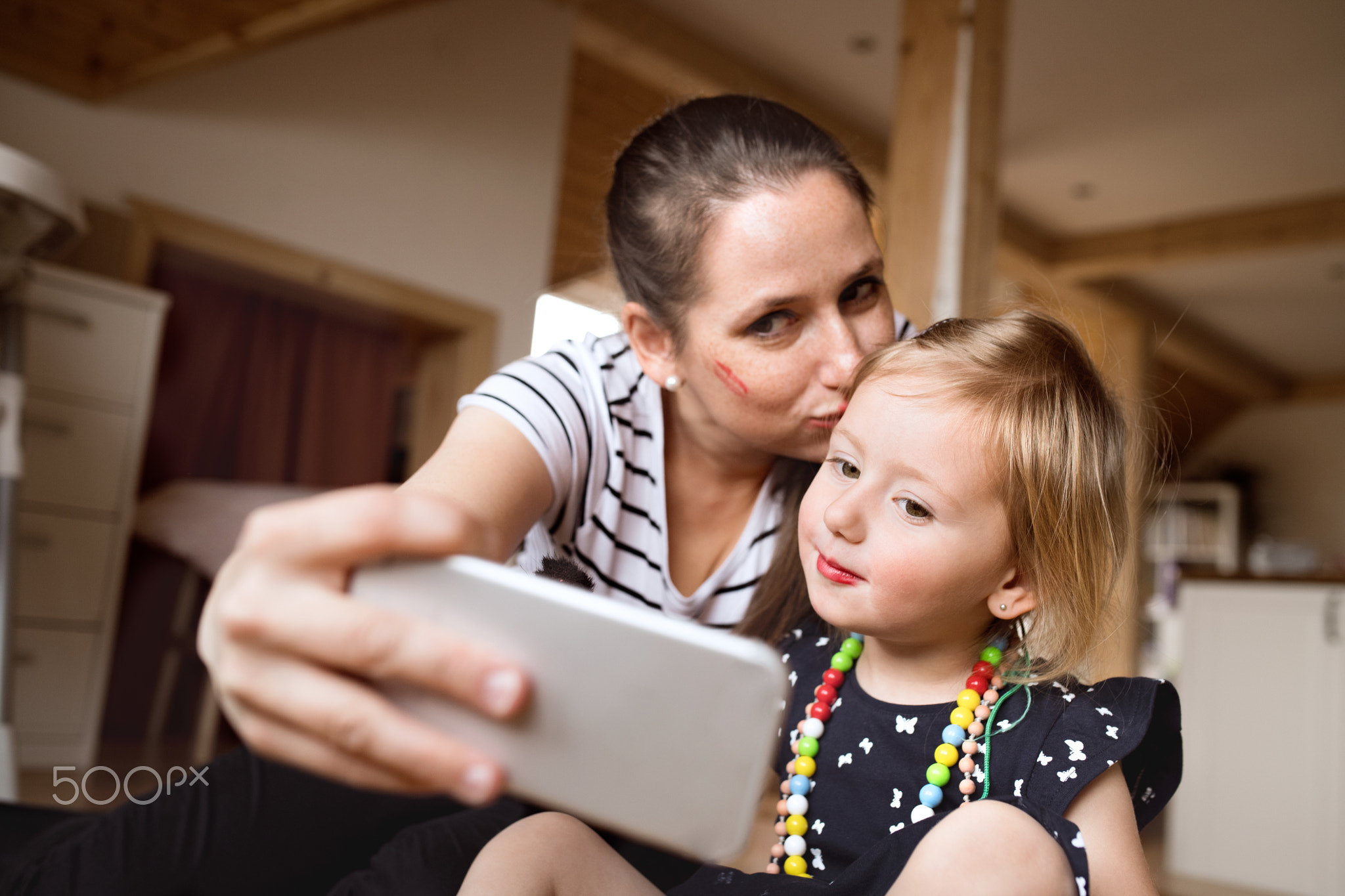 Beautiful mother and daughter taking selfie with smartphone.