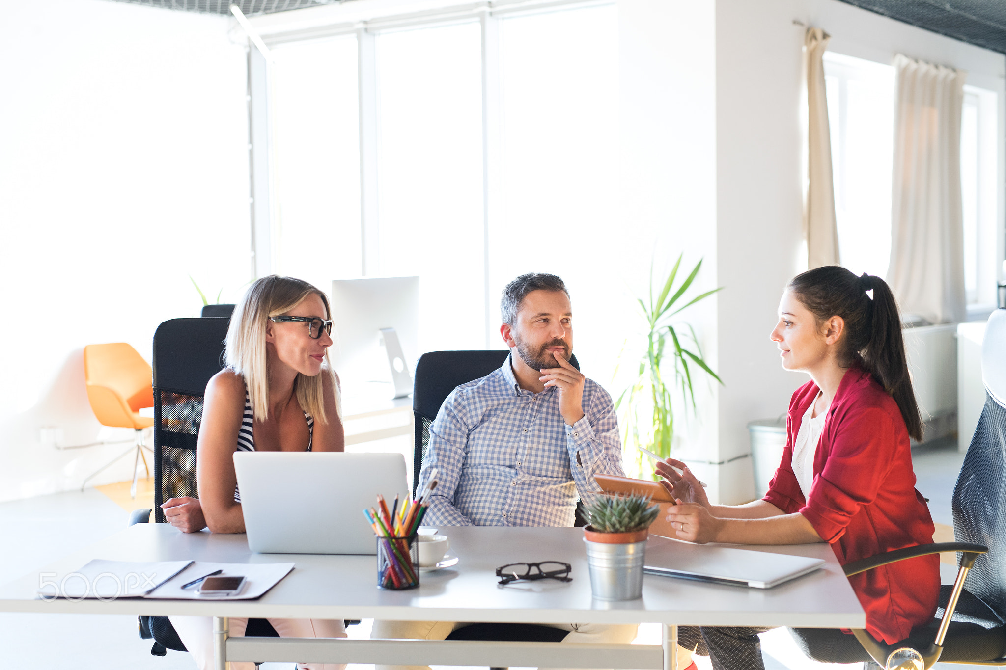 Three business people in the office talking together.