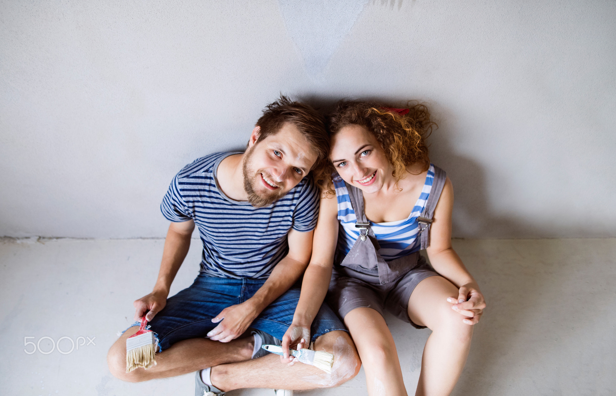 Young couple in love painting walls in their new home.