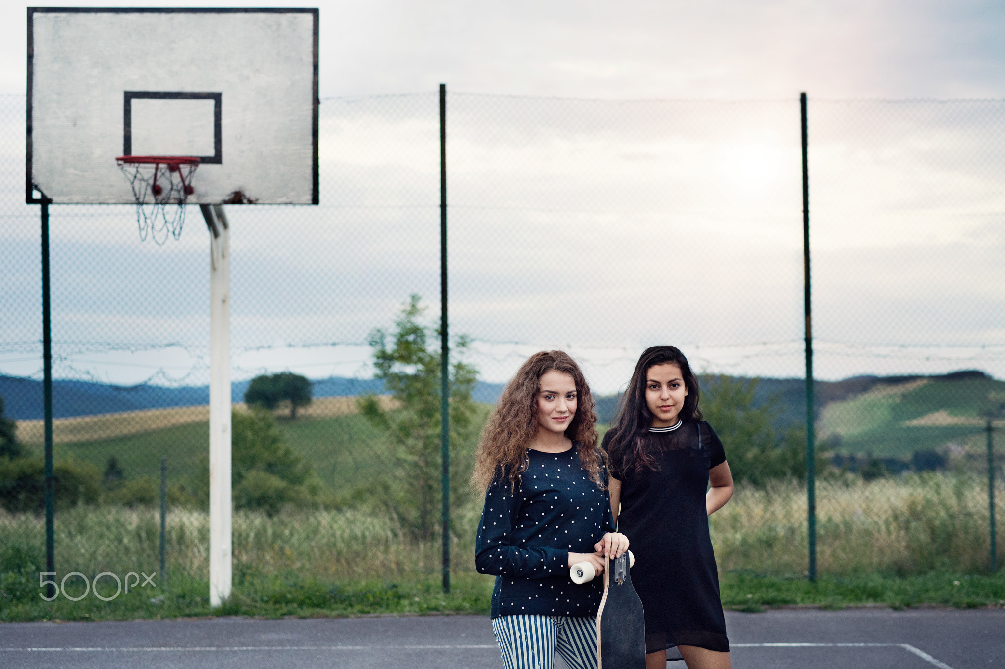Two attractive teenage girls outdoors on playground.