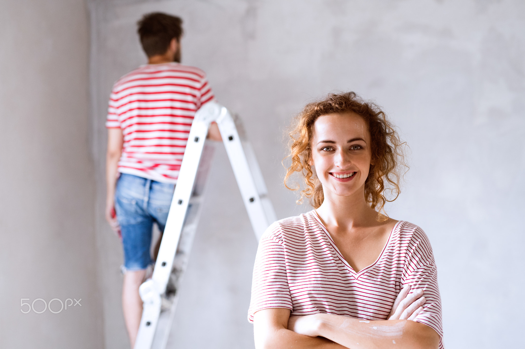 Young couple painting walls in their new house.