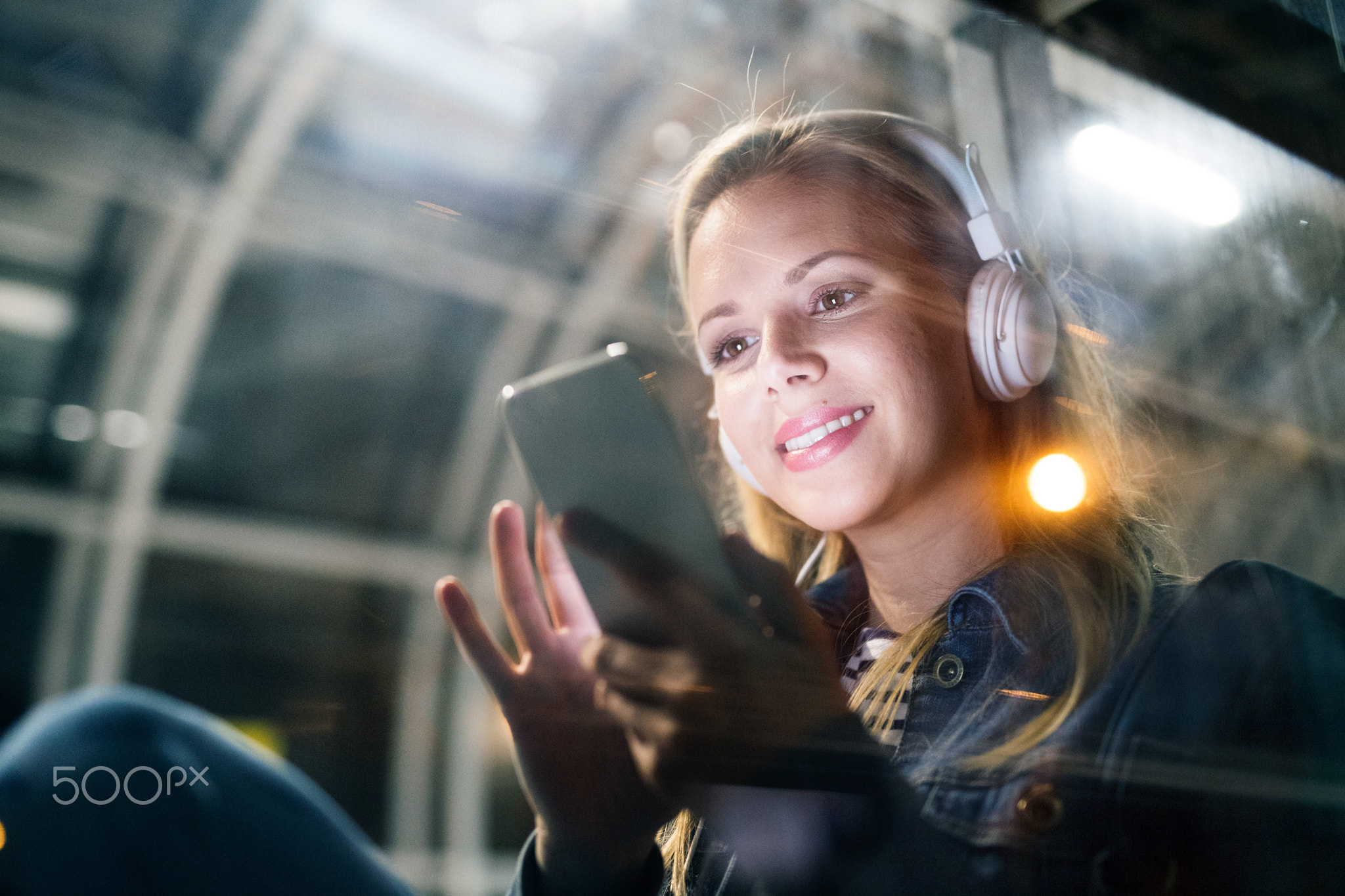 Woman in the city at night holding smartphone, texting.