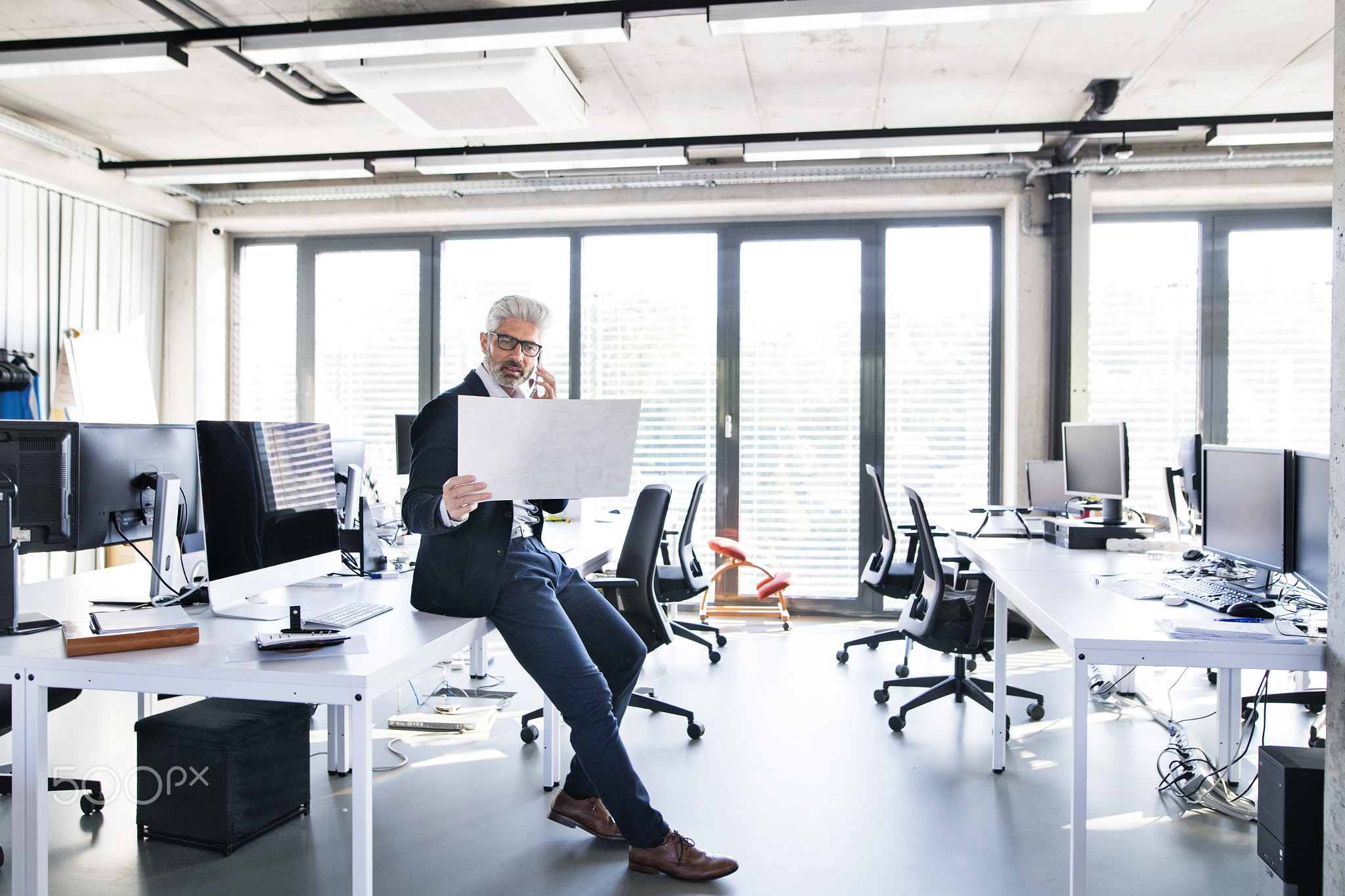Mature businessman in the office making a phone call.