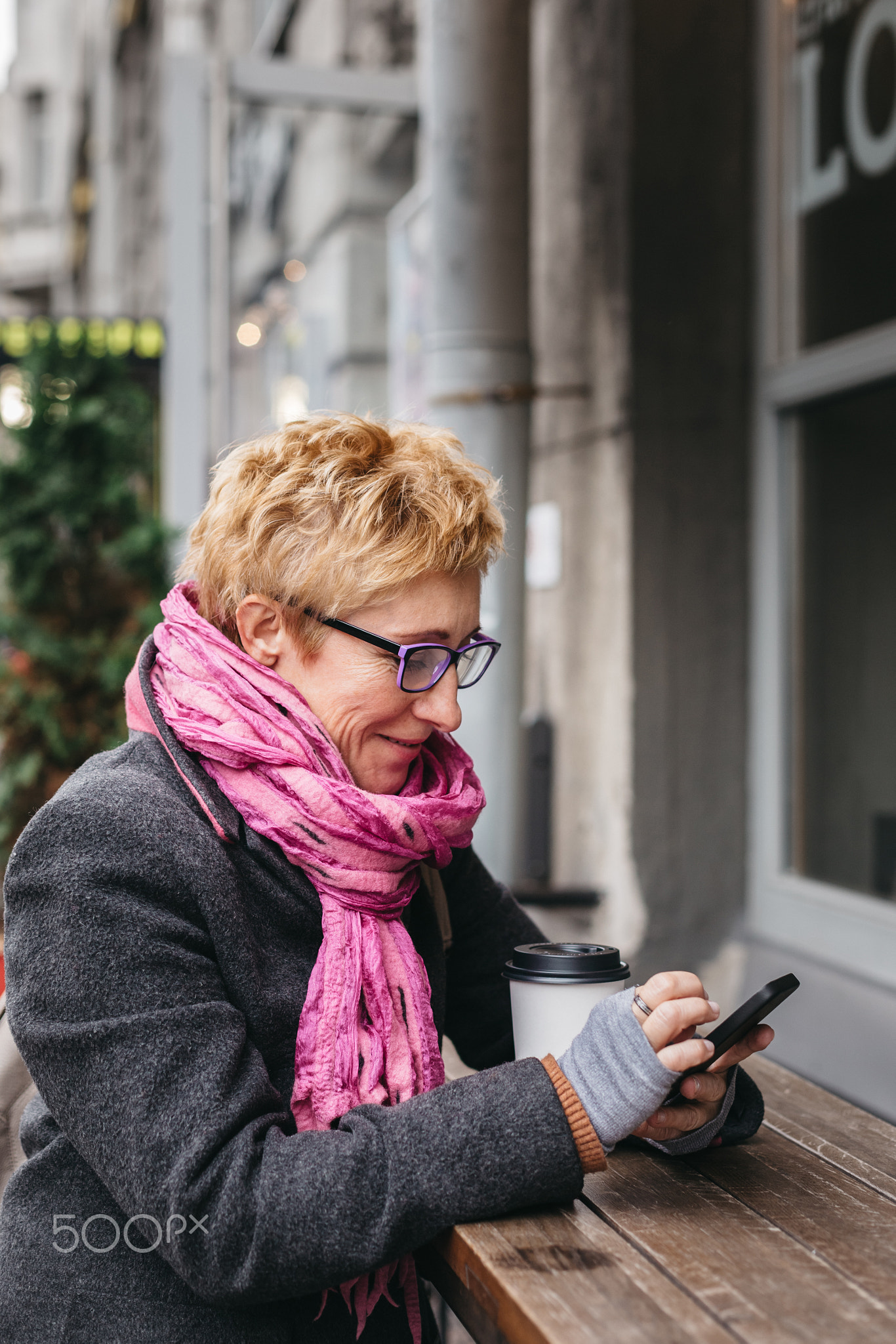 Woman browsing smartphone in outside cafe