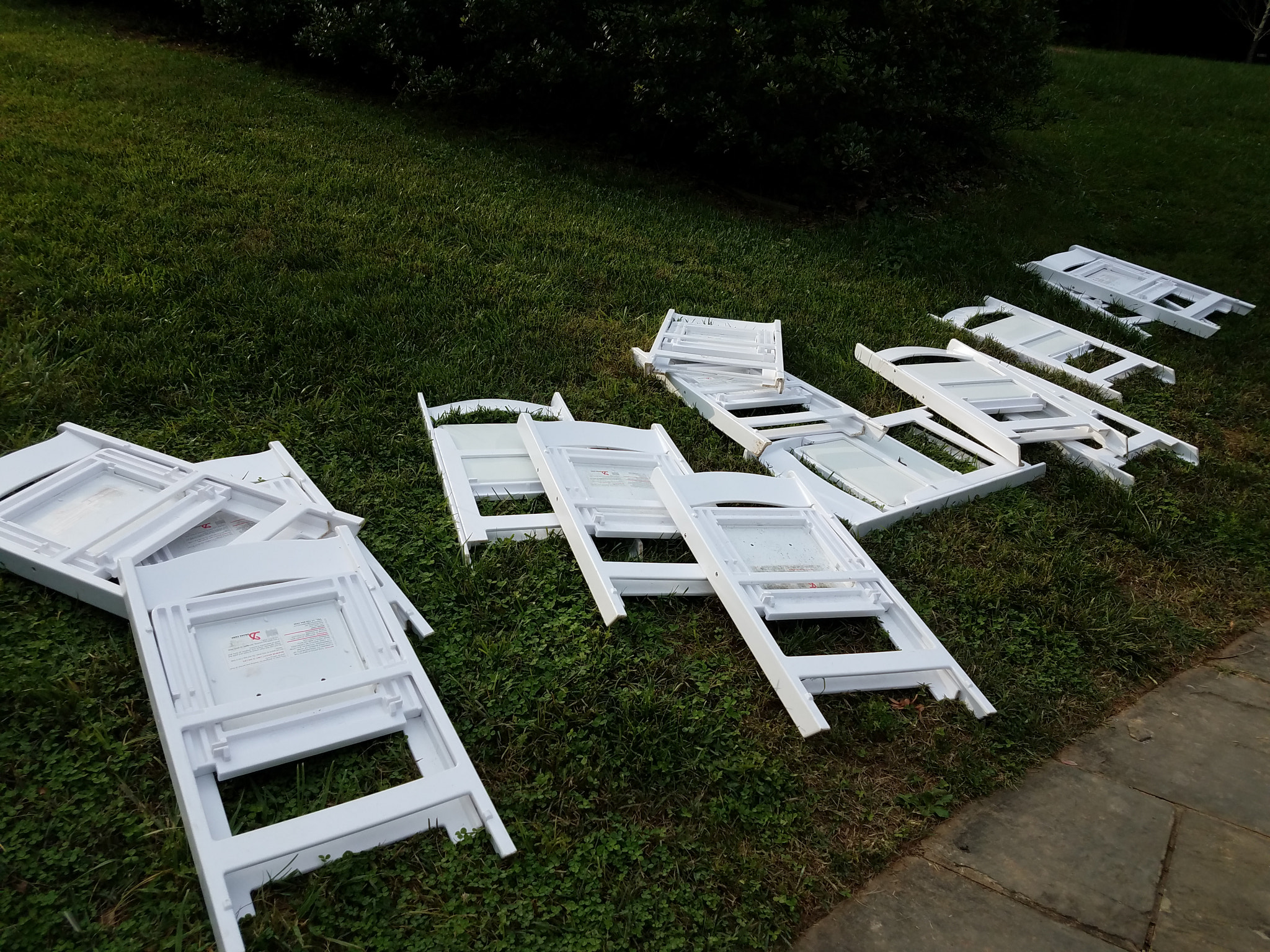 white plastic chairs folded on the ground