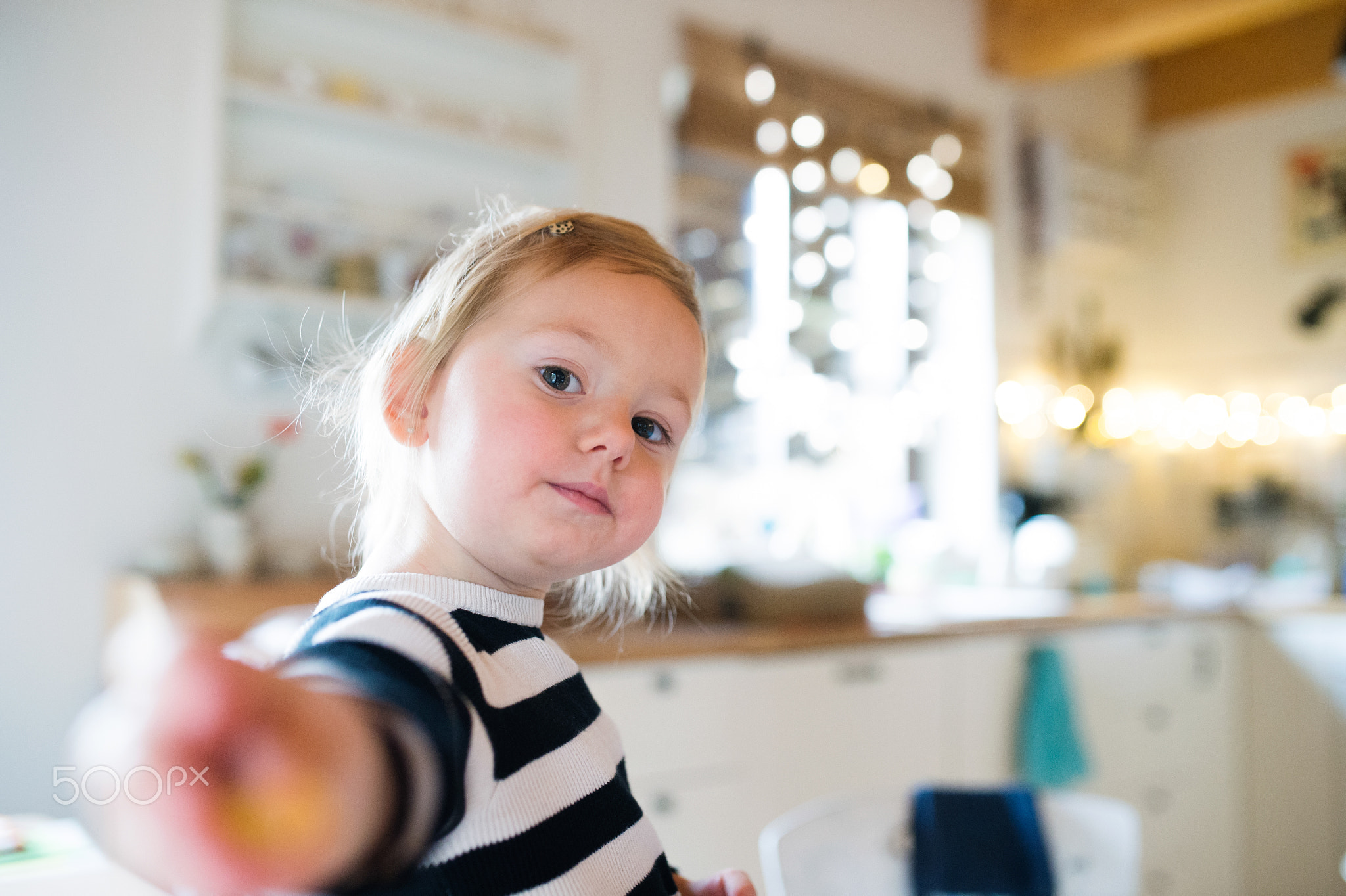 Cute little girl in striped dress sitting on kitchen table. Chri