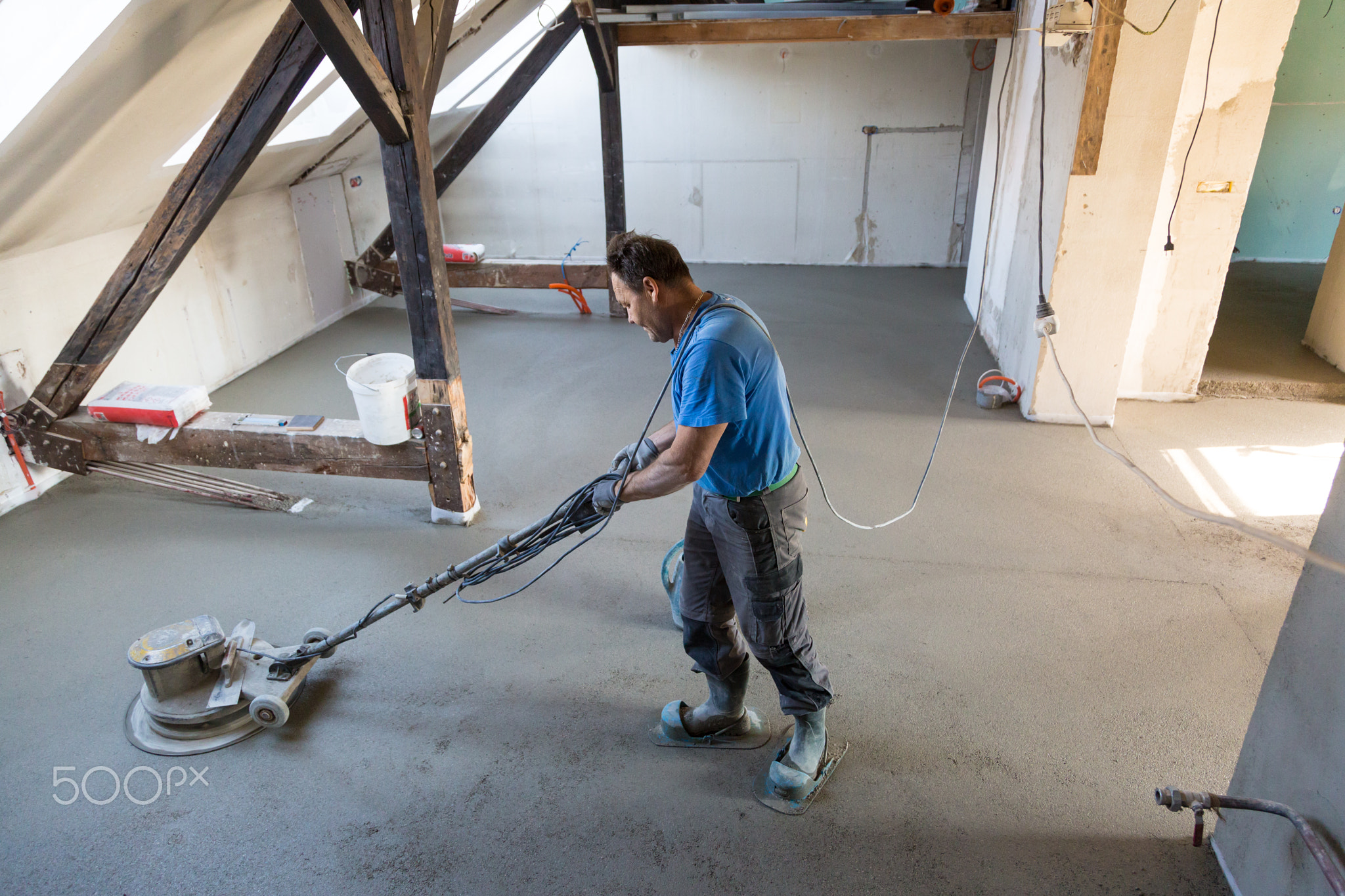 Laborer polishing sand and cement screed floor.